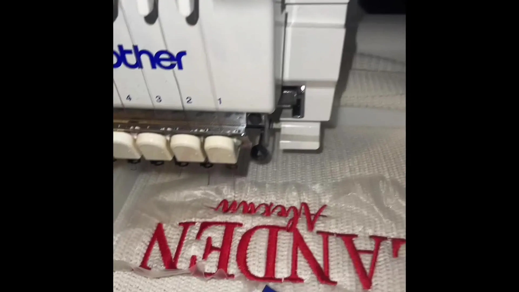 A finished name embroidery sits cleanly on a chunky knit sweater while still in the magnetic hoop, showing crisp satin edges and stable placement.