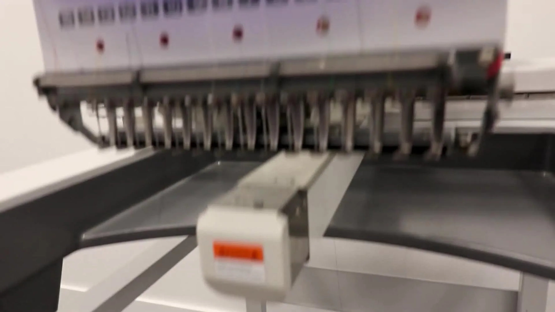 A commercial Ricoma multi-needle embroidery machine stitches a sneaker using a specialty clamp, highlighting production-focused capability.