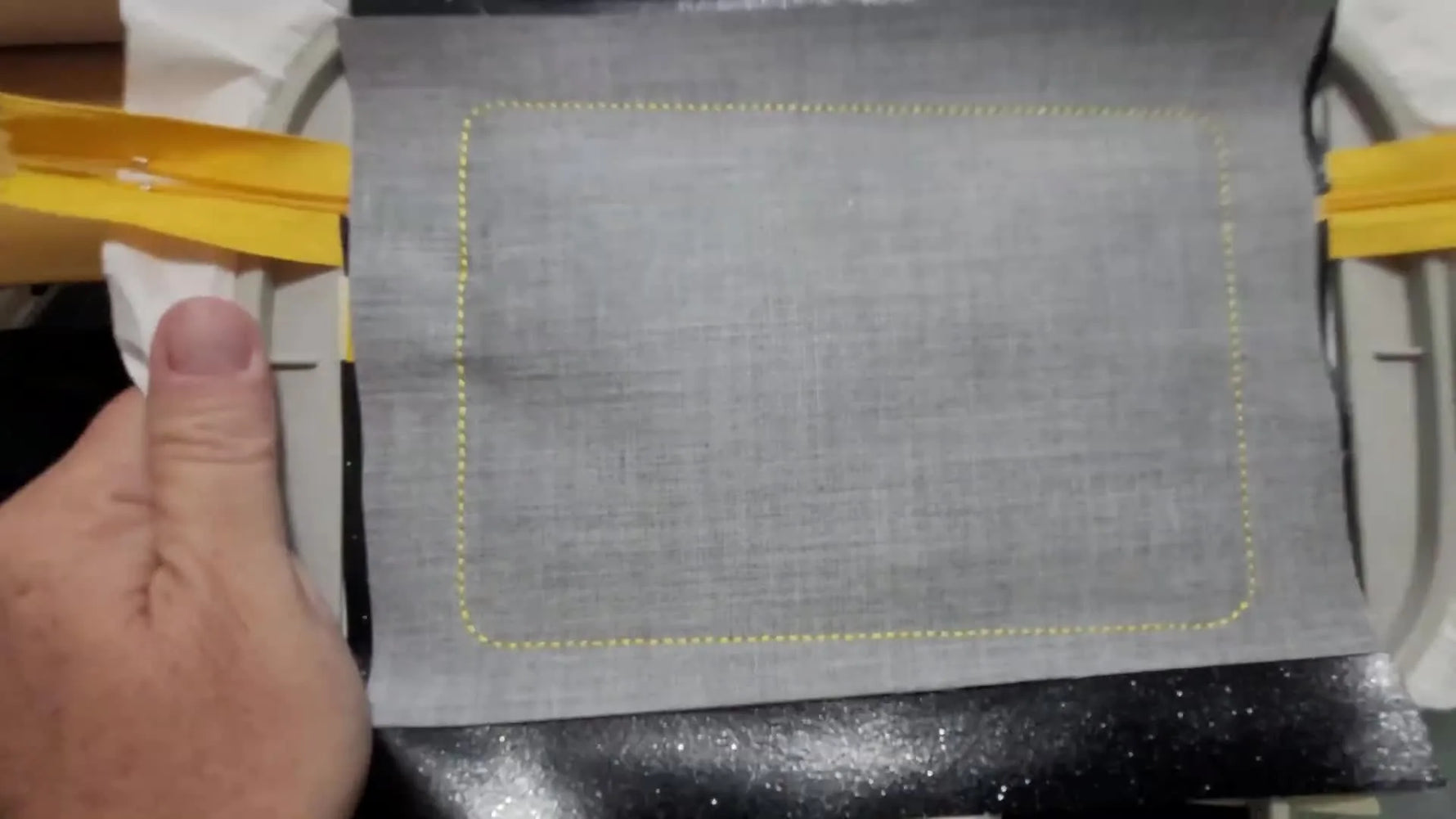 A finished upright ITH zipper bag with black glitter vinyl, a yellow zipper, and a stitched “LOVE” paw print reverse appliqué design.