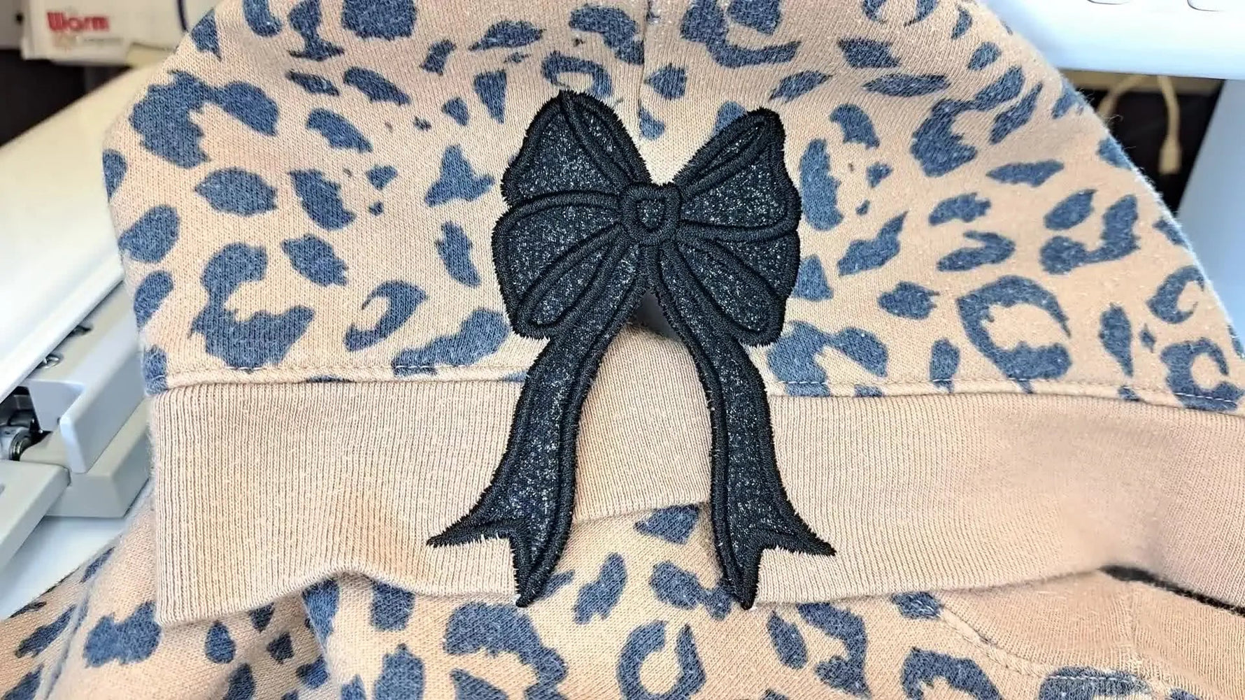 Finished side seam applique bow on a leopard print sweatshirt.