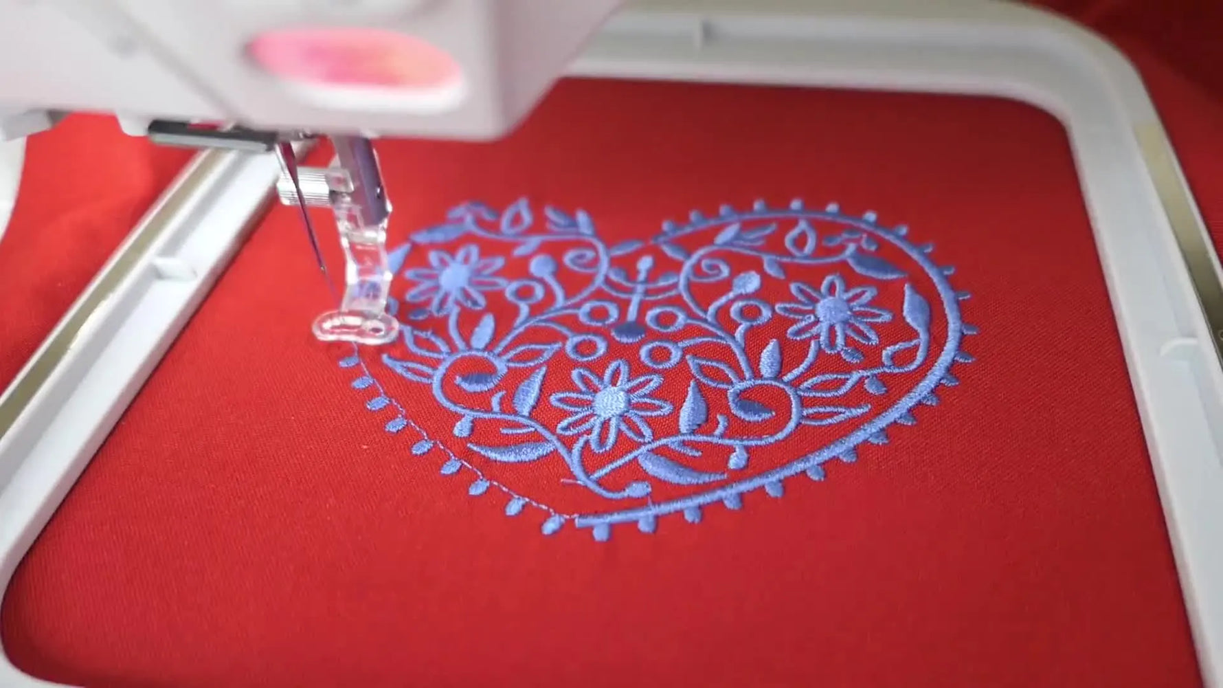 A close-up of the Elna eXpressive 850 stitching a nearly finished heart embroidery, showing clean density and crisp edges.