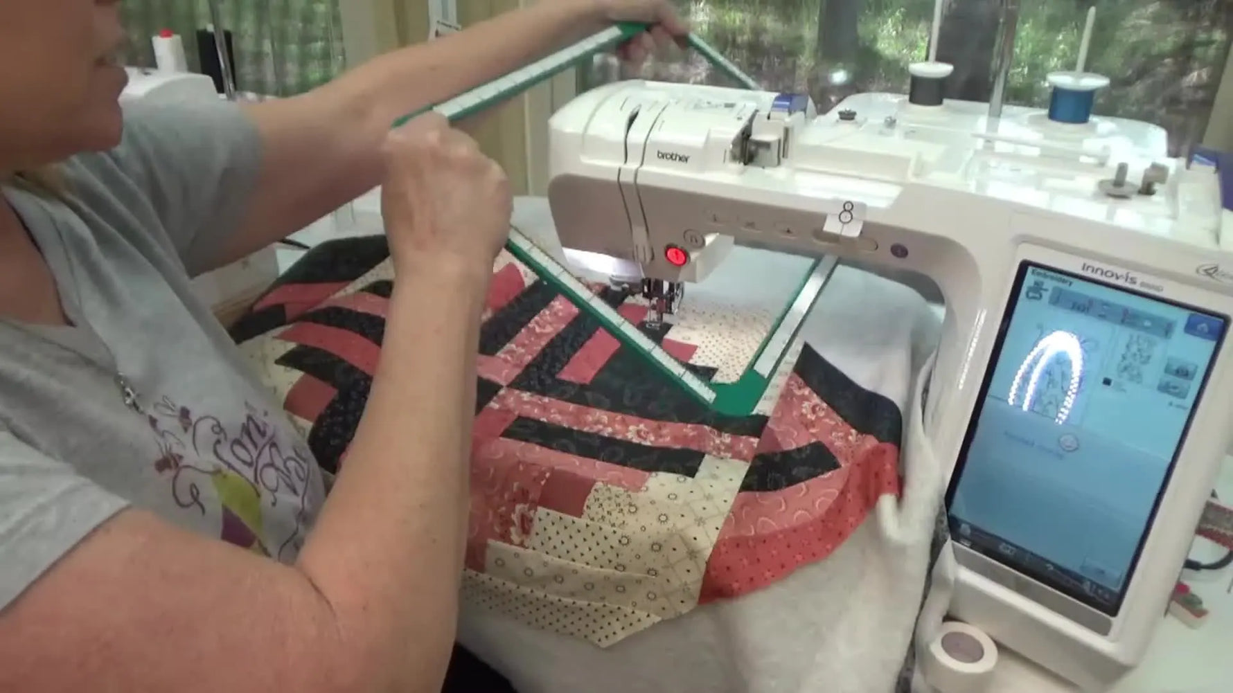 The host lifts the top ring of a magnetic hoop to slide a bulky quilt sandwich smoothly for the next connected quilting pass.