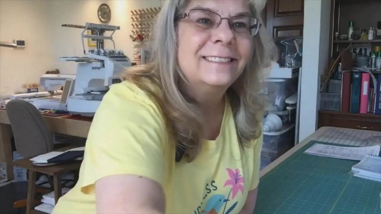 The Brother PR1055X is shown fully set up on a table with the screen lit, ready for first stitches.