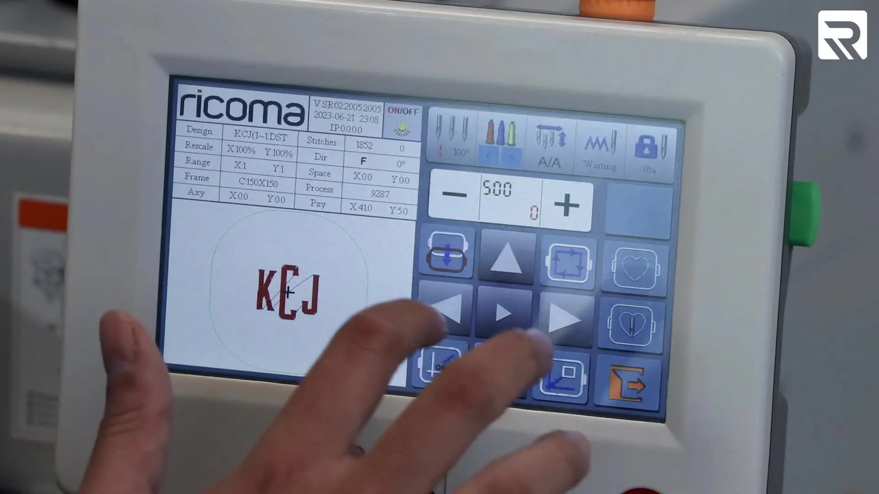 Close-up of the Ricoma MT-1501 stitching a white monogram on a black duffel bag held firmly in a blue magnetic hoop.