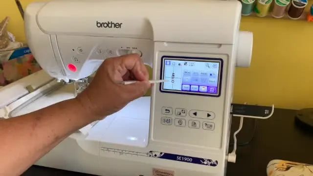 A close-up shows the Brother SE1900 tracing the design boundary so you can confirm the needle will land safely inside the leash edges before stitching.