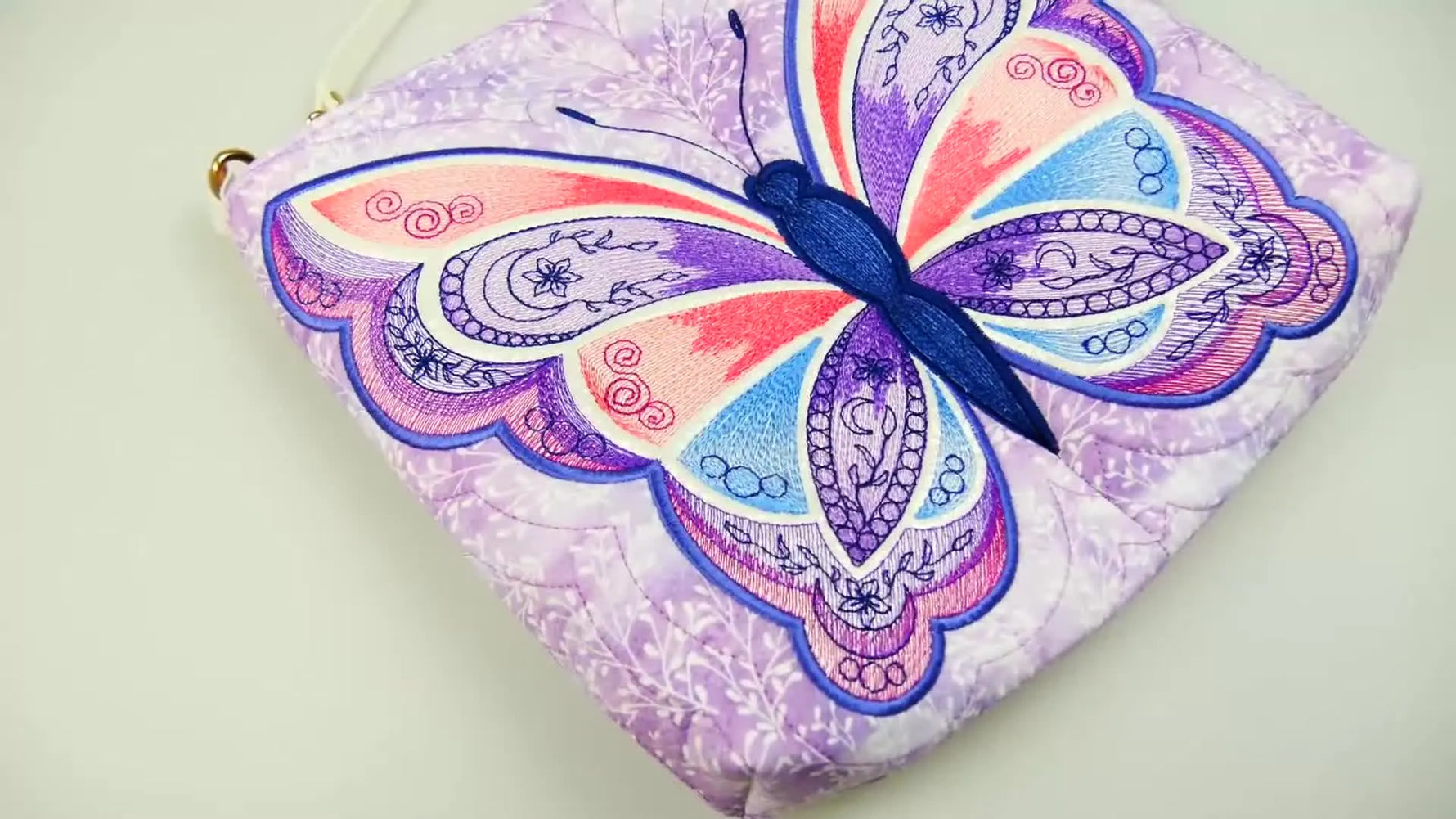 A close-up of the finished Butterfly Bag showing the completed embroidery panel and strap hardware.