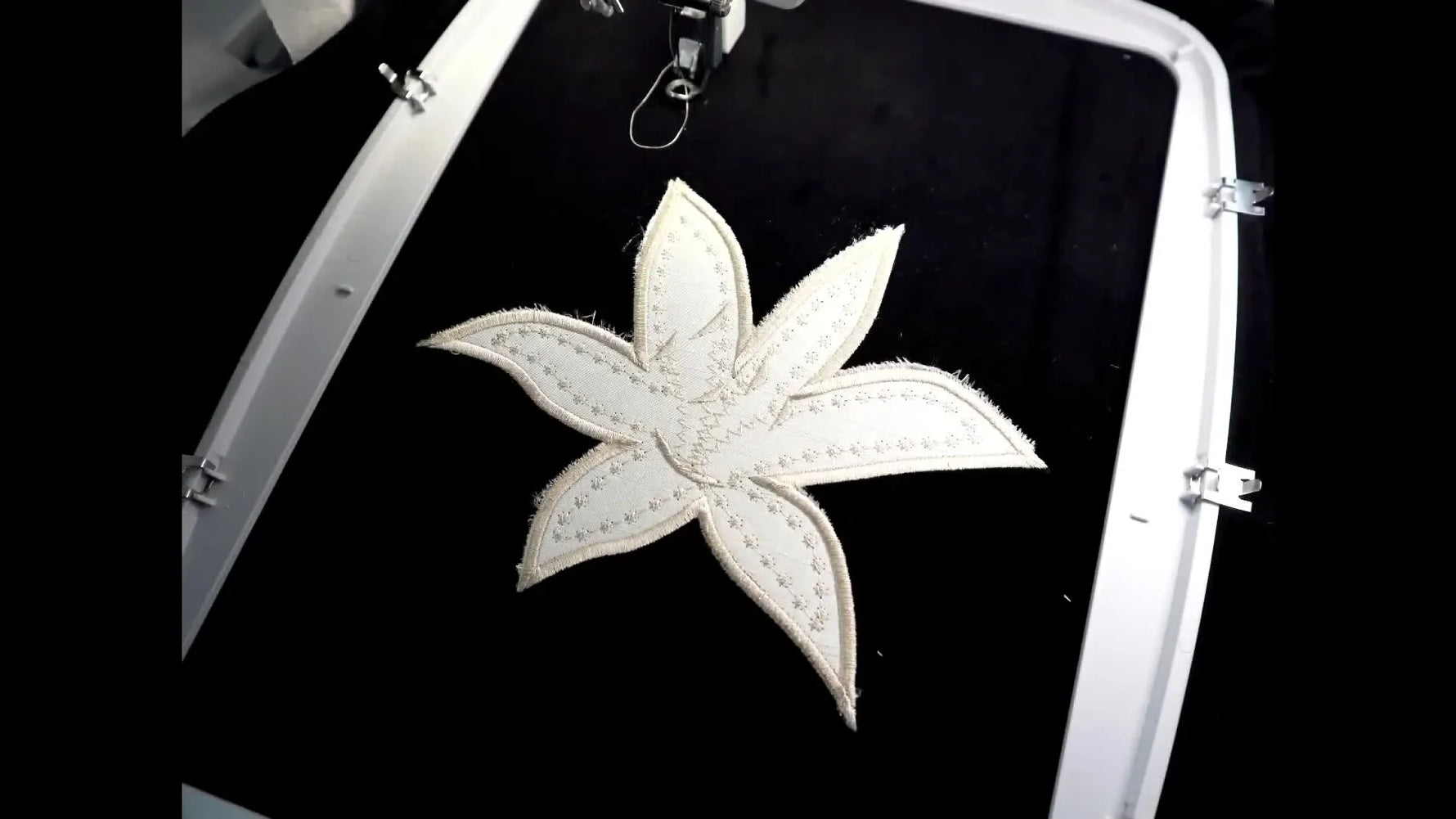 A finished flower appliqué stitched on black velvet, shown flat with an overlay indicating planned bead placement.