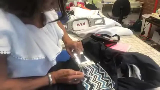 Close-up of double-curved scissors trimming appliqué fabric right up against the tack-down stitch line for a crisp patch edge.