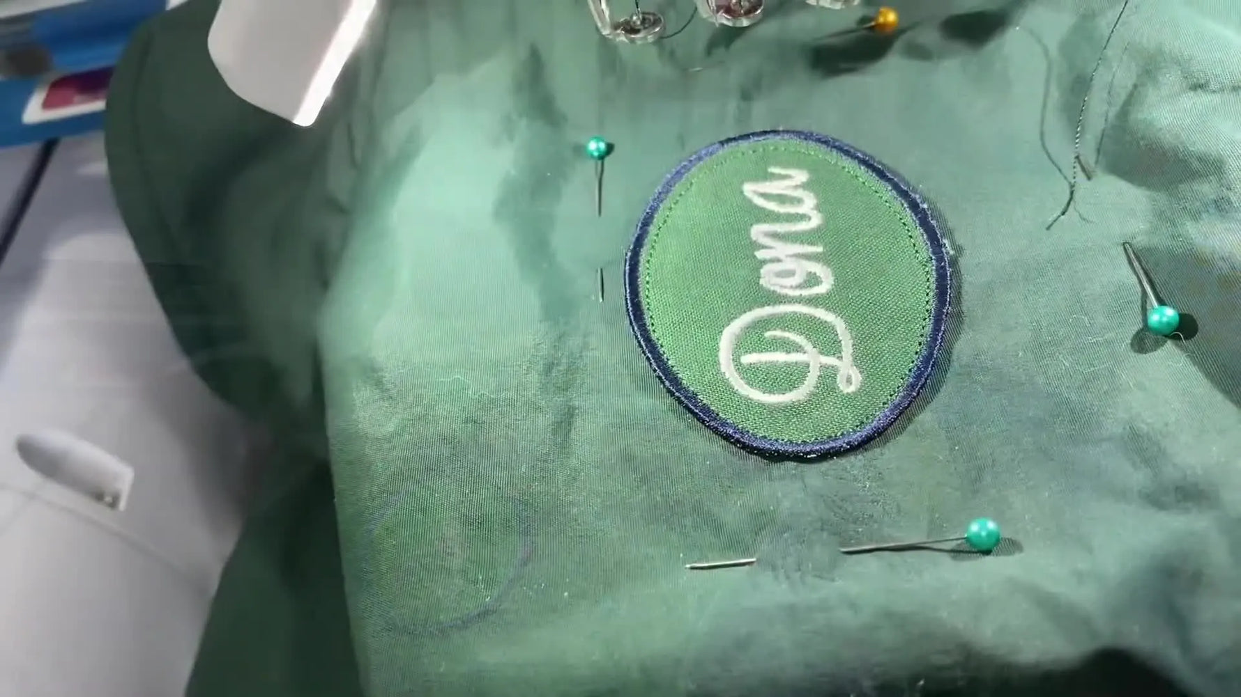 The finished jacket is held up to the camera, showing a neatly attached name patch covering prior embroidery damage.