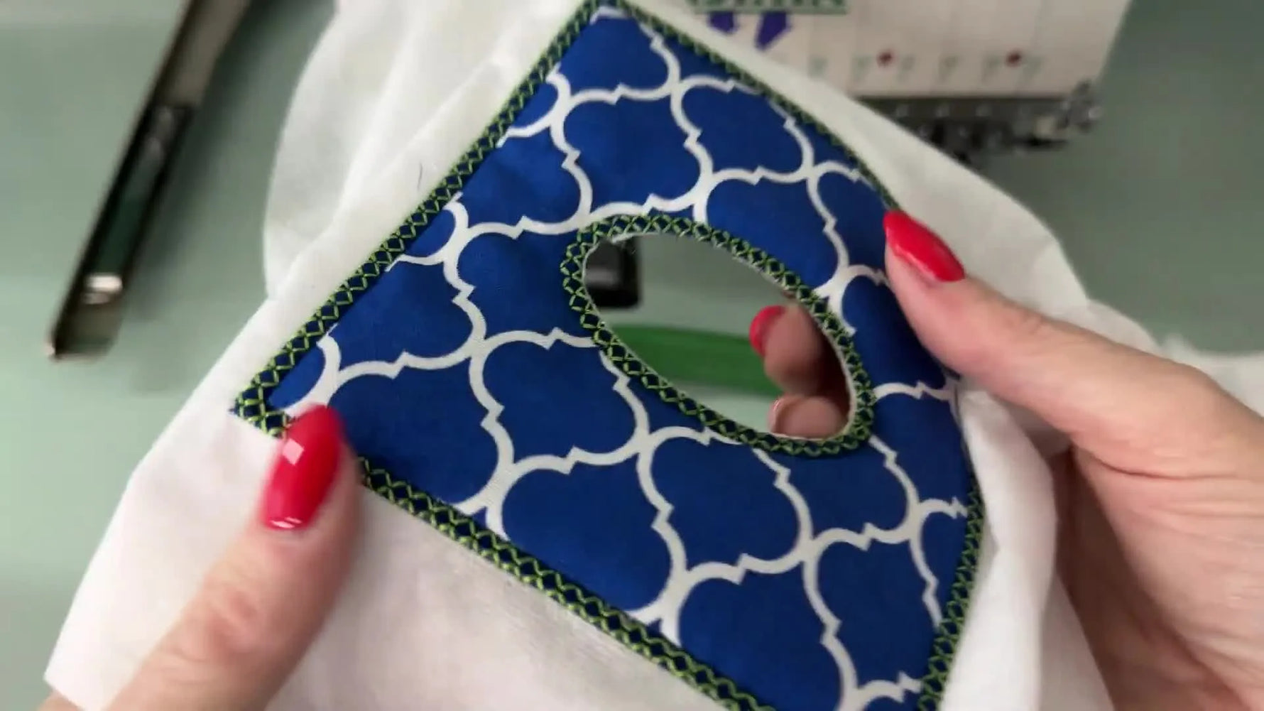 A finished top panel is held up close, showing a clean satin-stitched tissue opening and tidy edges ready for assembly.