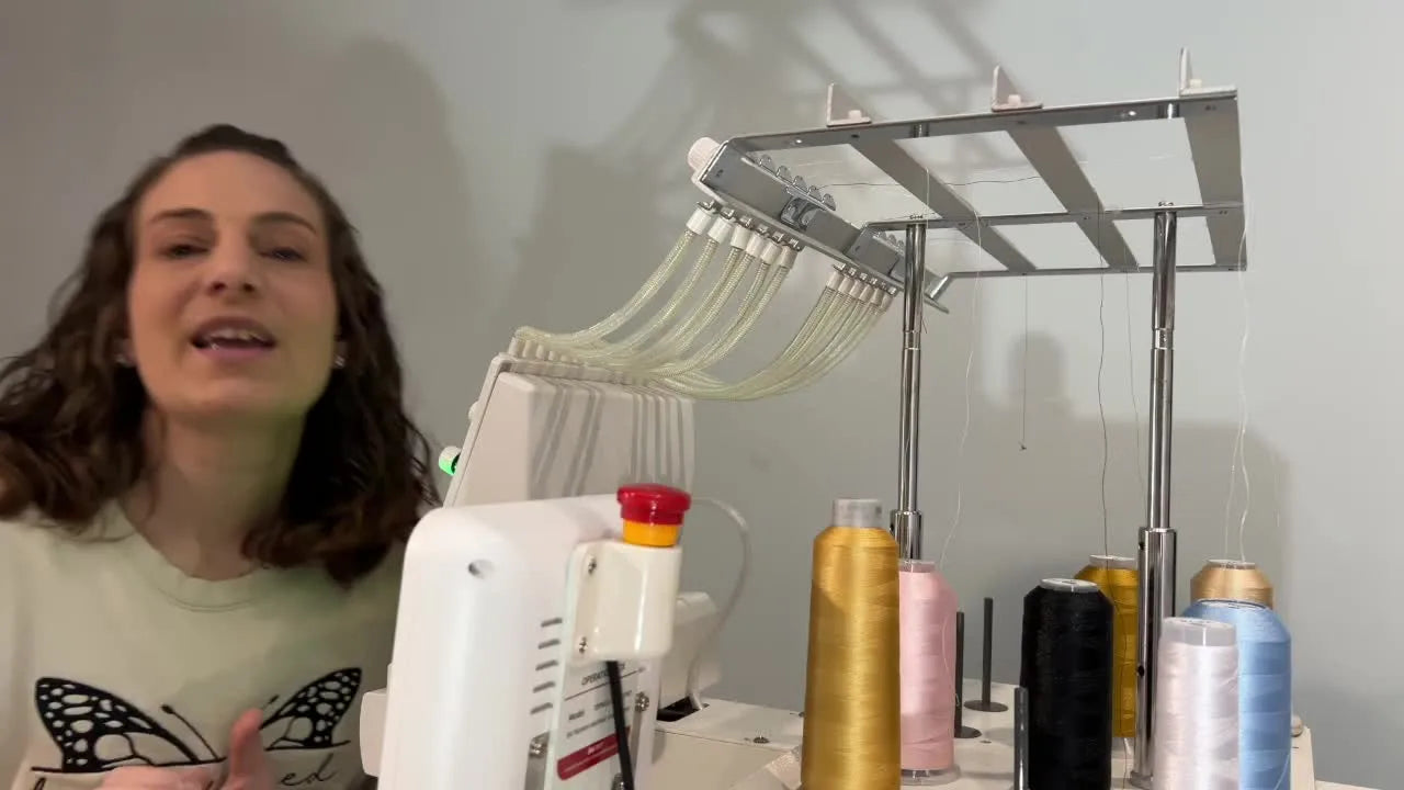 A presenter stands beside a BAI 15-needle embroidery machine with the guide tubes and thread stand clearly visible.