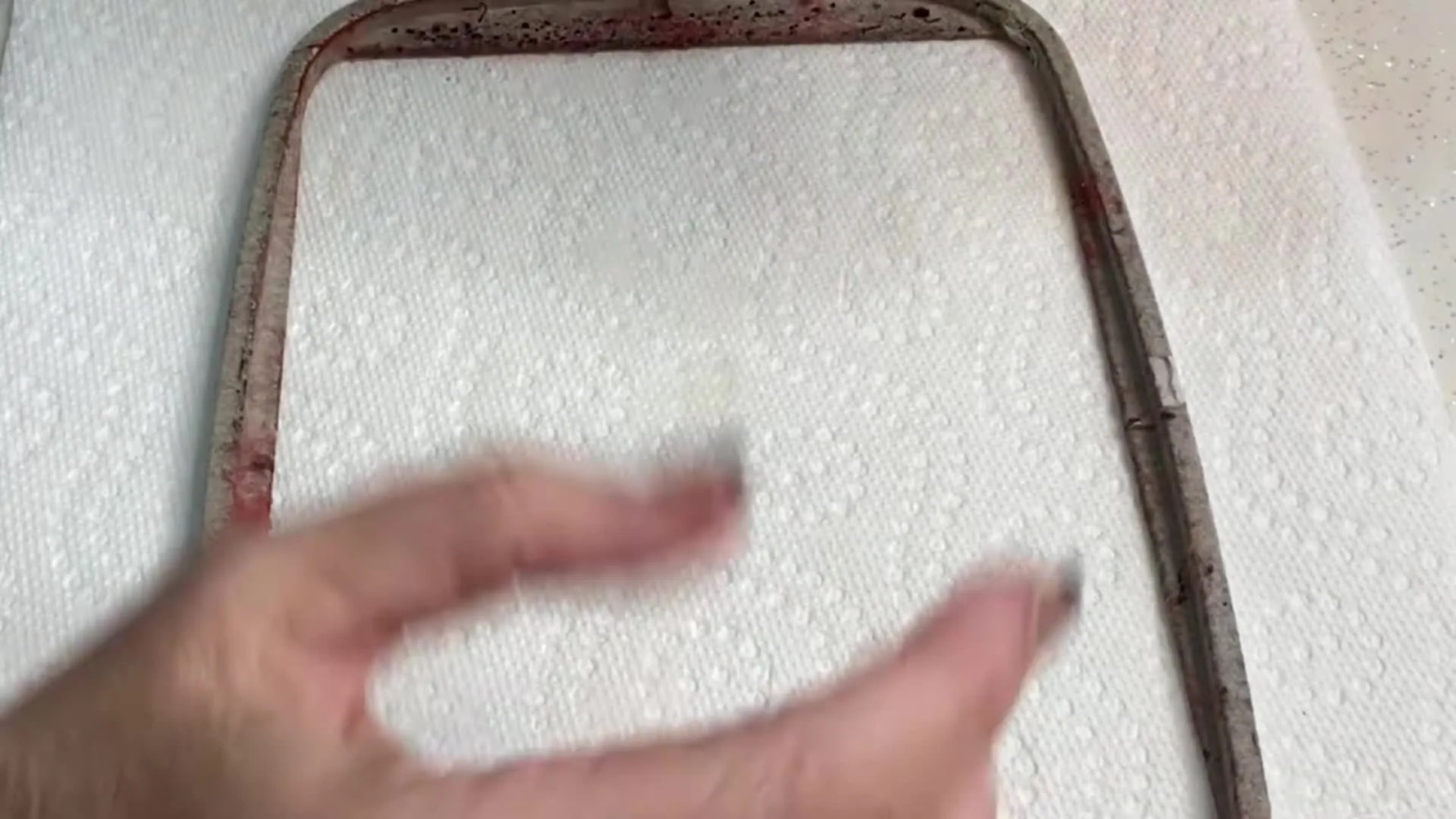 A close-up of the Goo Gone Spray Gel bottle held up clearly, the exact product used to dissolve stubborn adhesive residue on embroidery hoops.