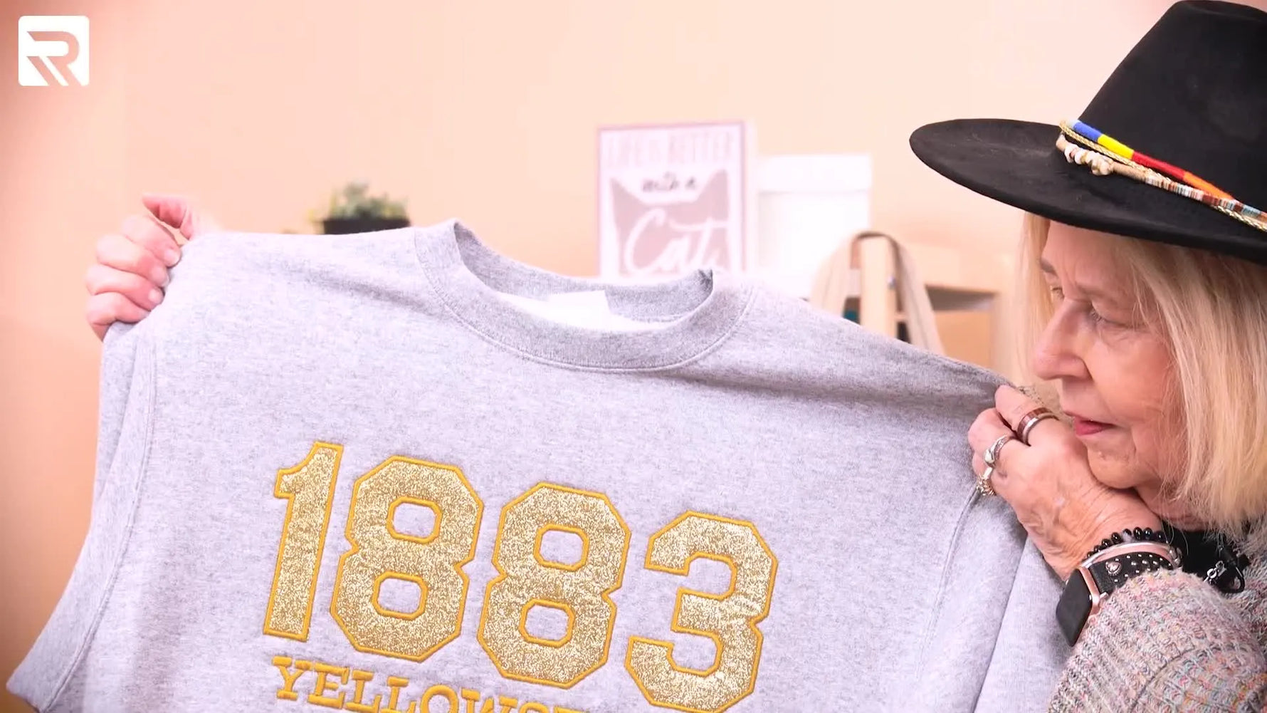 A finished grey sweatshirt shows the gold glitter “1883 Yellowstone” appliqué with clean satin borders and a straight, centered layout.