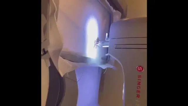 Close-up action shot of the Singer Superb stitching a satin-stitch letter in pink thread on white fabric.