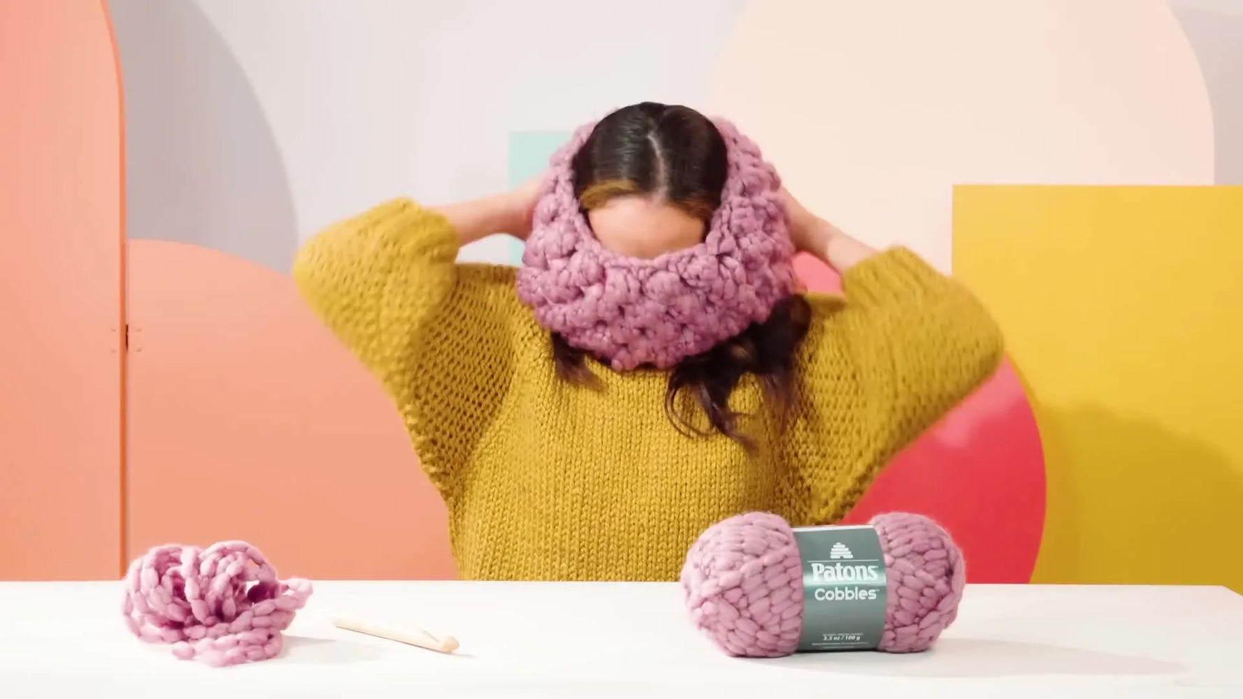 A woman wearing a color-block knit hat, smiling at the camera.