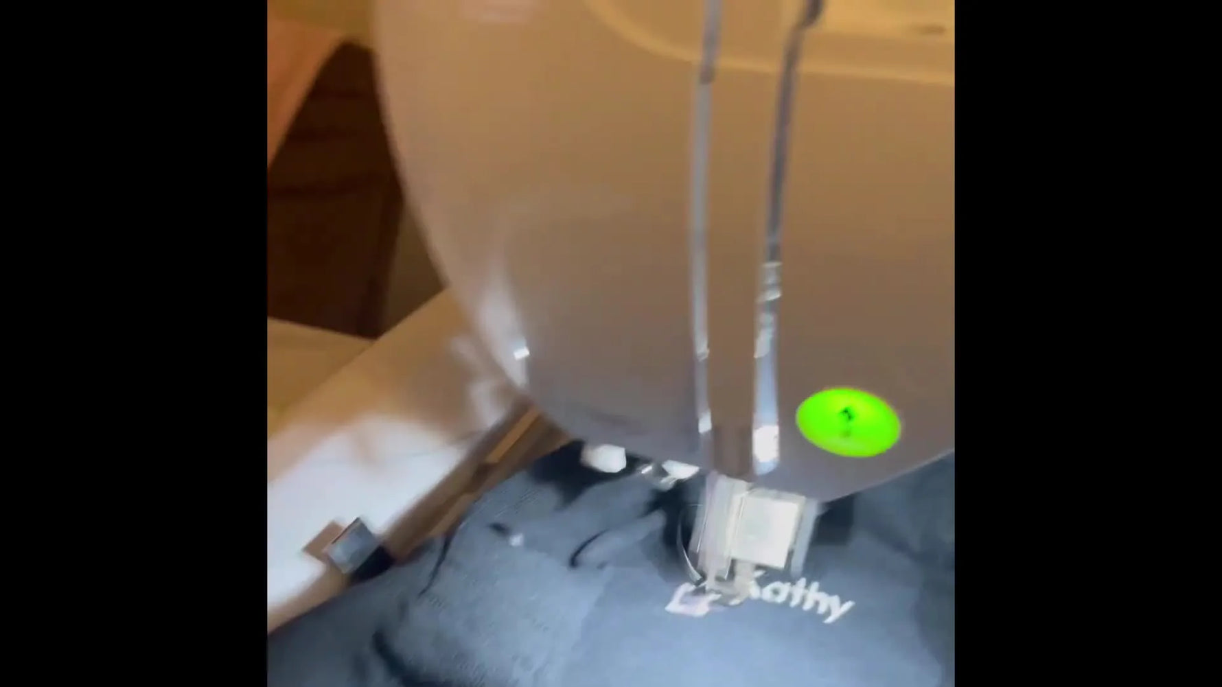A close view of a hand pulling excess polo fabric away from the needle area while the Brother PE900 stitches, preventing the shirt from being sewn shut.