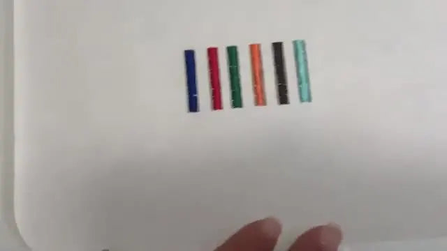 An overhead view of a completed Brother PR multi-needle tension test sample with six colored satin bars stitched on stabilizer.