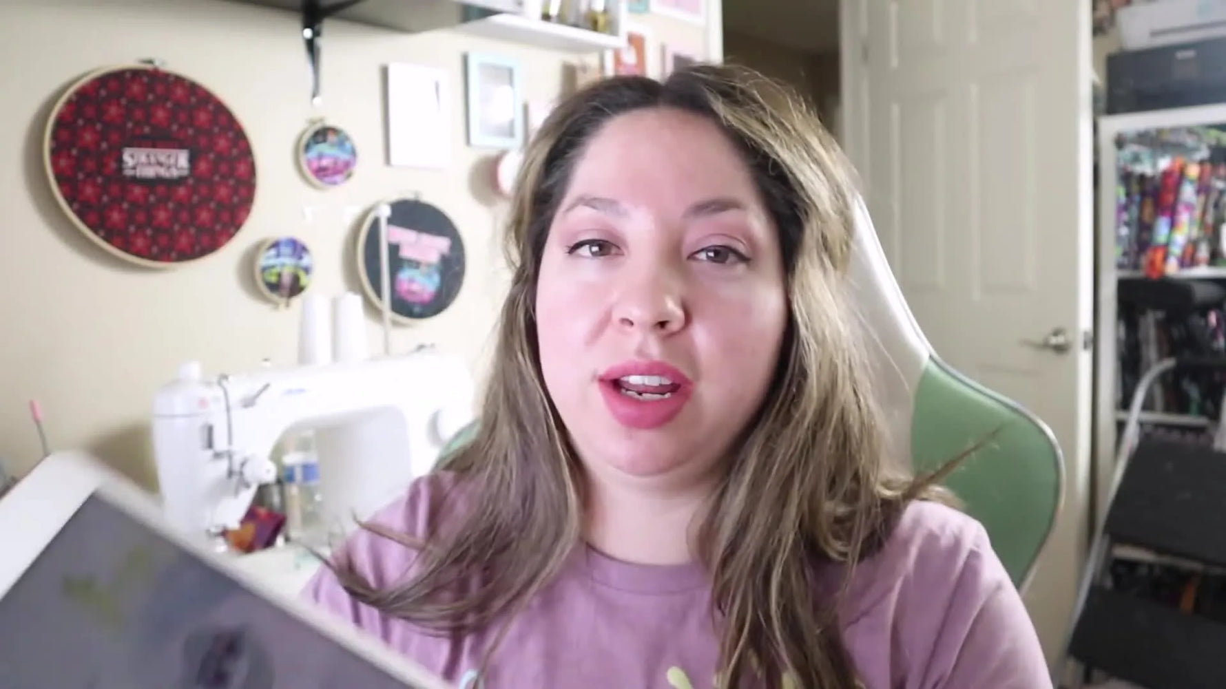 Woman holding up a tablet displaying an embroidery design PDF.