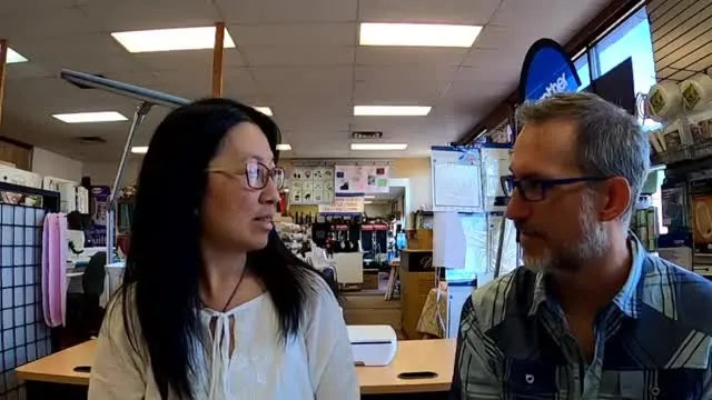 Michelle holds up two finished Sweet Pea Flower Power Zippy Bags, showing the vinyl appliqué flowers and the in-the-hoop construction.
