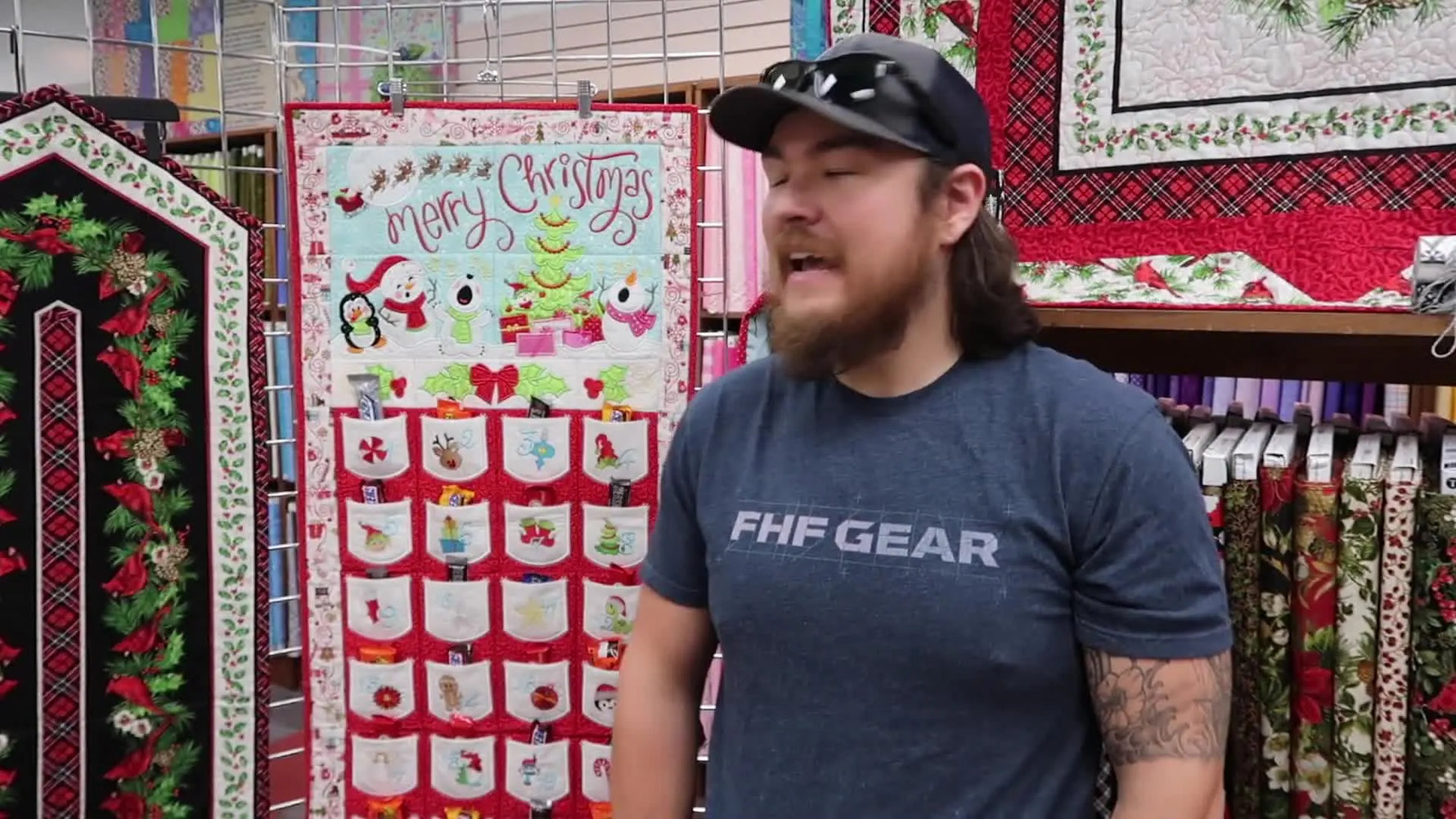 A finished, heirloom-style Christmas Advent Calendar quilt hangs on display, showing the full layout and pocket grid.