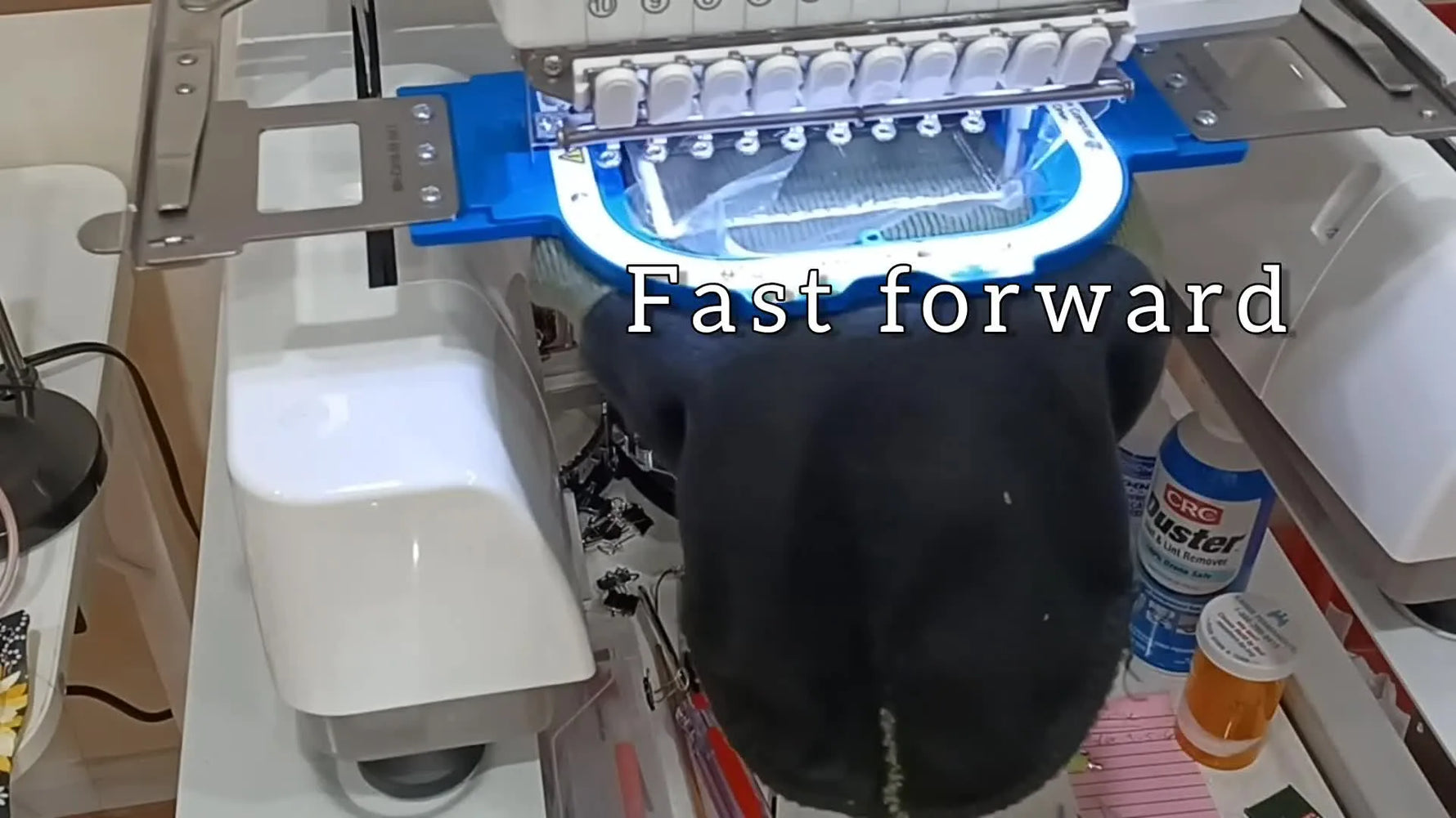 A close-up of the Ricoma multi-needle machine stitching a personalized name onto a knit beanie inside a magnetic hoop.