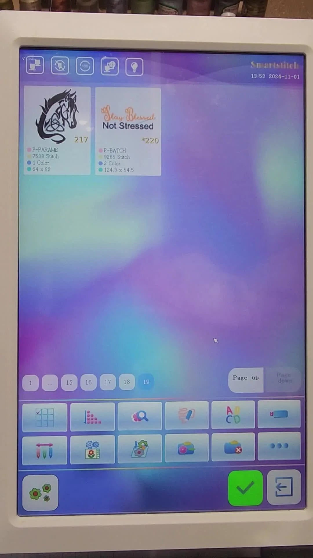 SmartStitch embroidery machine display showing two existing designs and menu options.