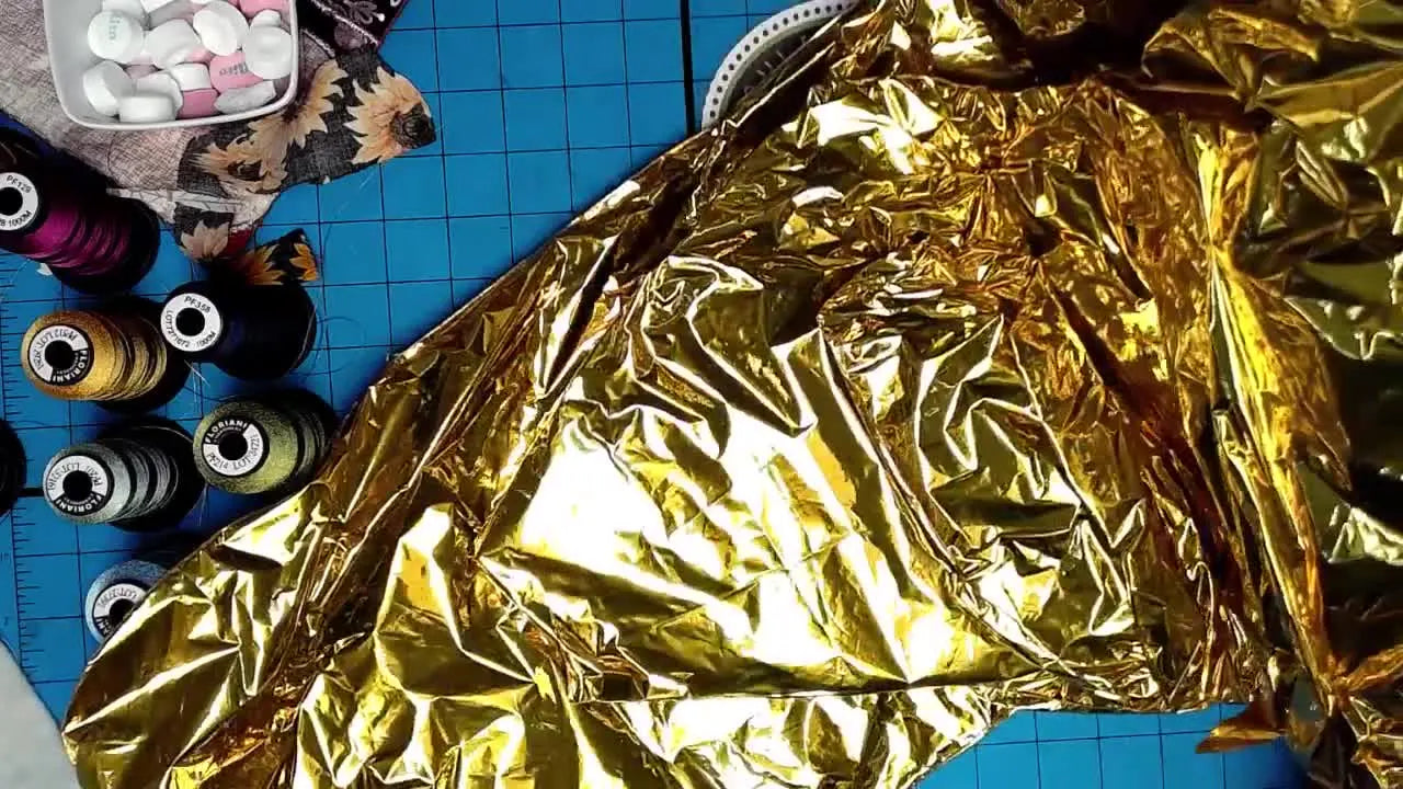 A close view of a gold Mylar balloon being used as a budget-friendly substitute for craft Mylar sheets in a machine embroidery quilt-block project.