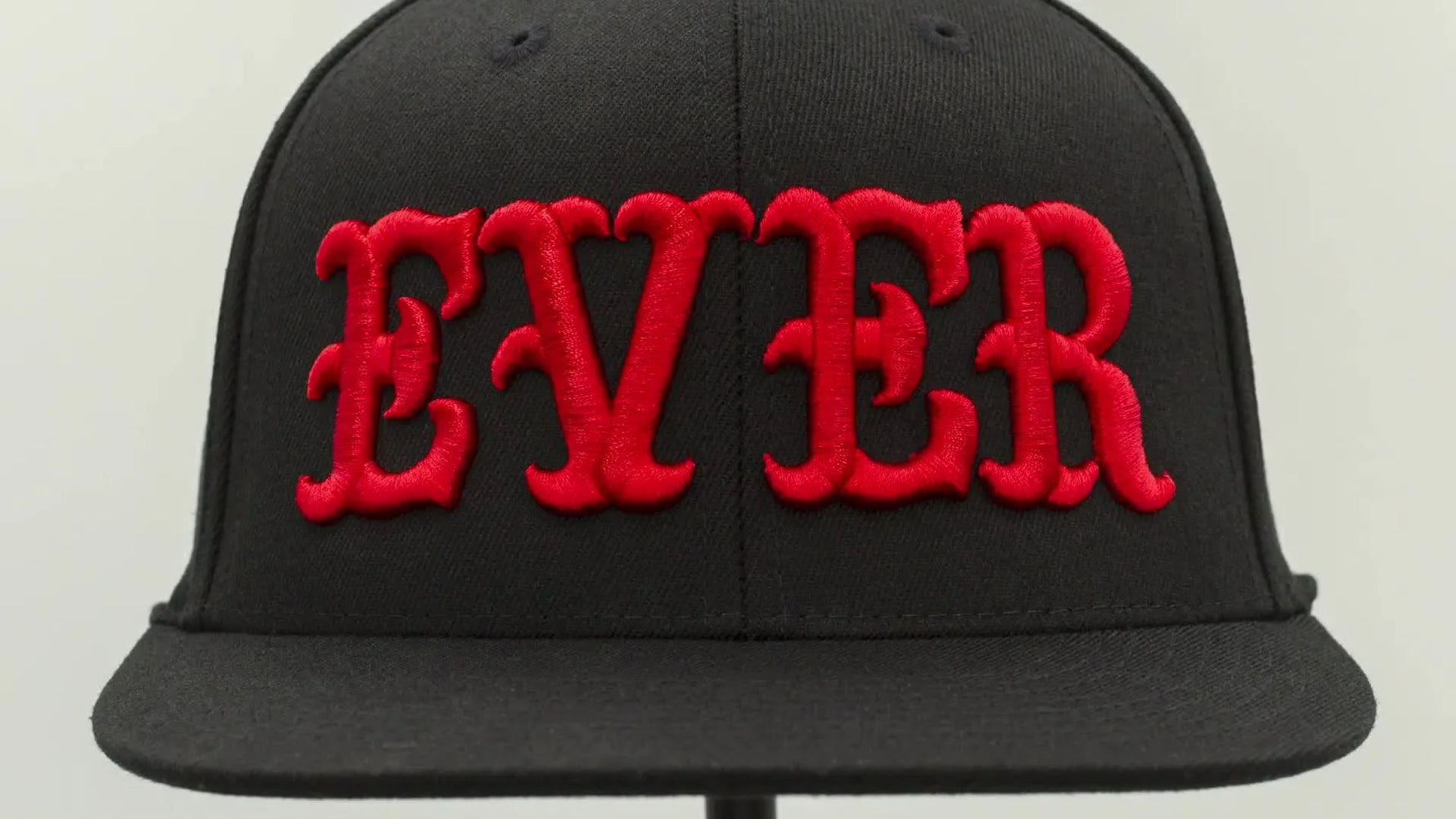 A pristine black structured cap with bold red “EVER” 3D puff embroidery shown in close-up, highlighting crisp edges and a clean finish.