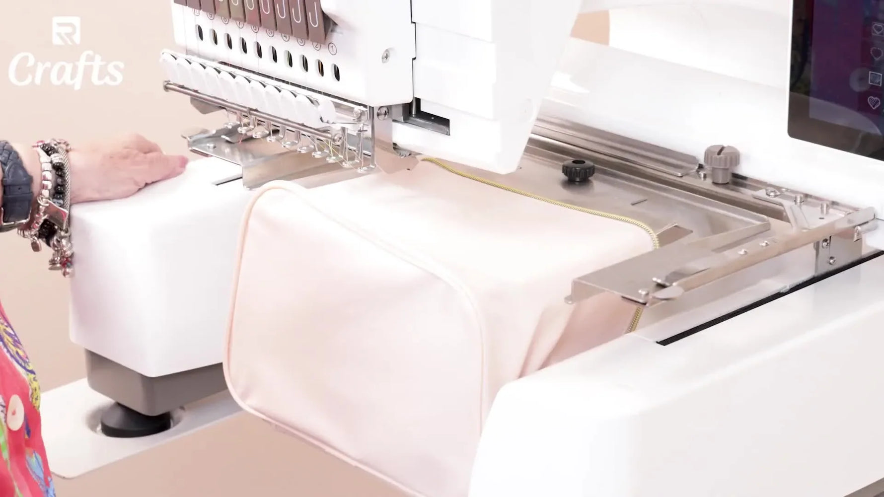 A close-up of the embroidery machine stitching a hot pink letter onto a small makeup bag held flat and stable in a magnetic hoop setup.