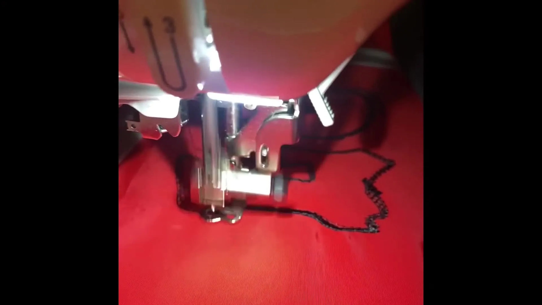 A full view of the red windbreaker’s back shows the finished black “GLO” outline stitched across a large area.