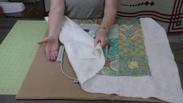 An overhead view shows a thick quilt sandwich being positioned over a 6.25×10 hoop with the bulk intentionally kept to the left for easier stitching on a standard embroidery machine.