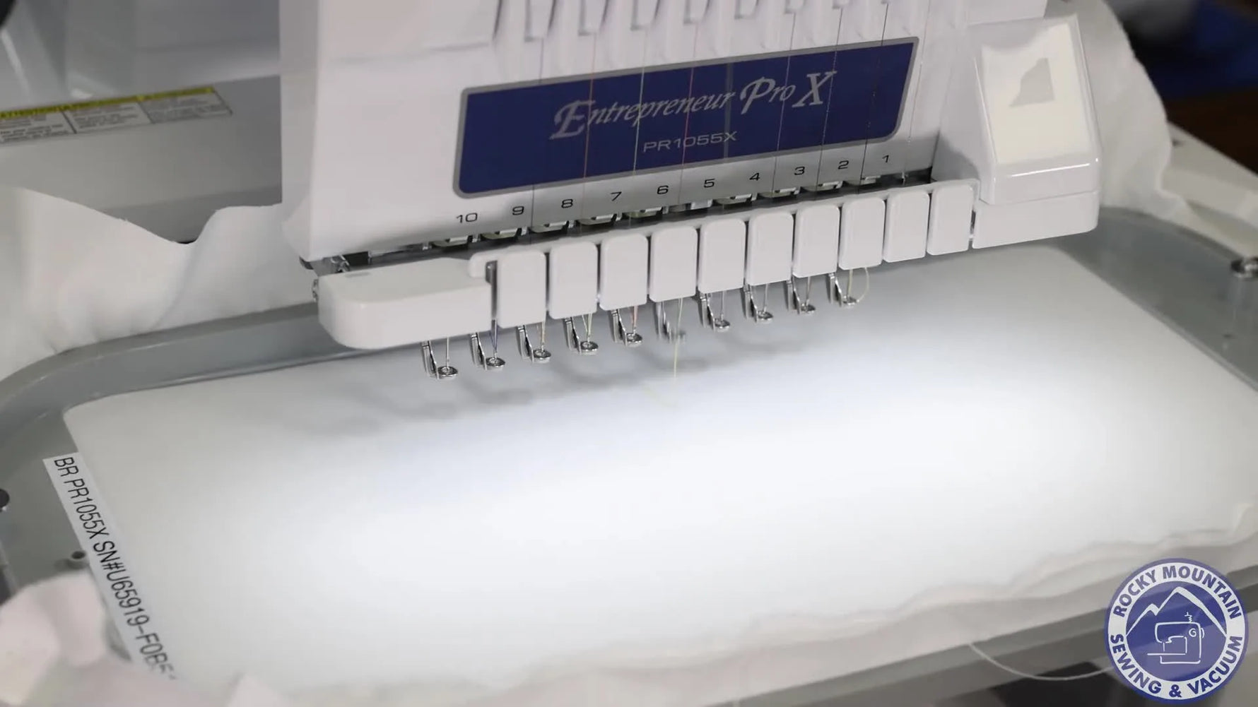 An extreme close-up shows the Brother PR1055X needle bar stitching at high speed, highlighting the machine’s multi-needle productivity.