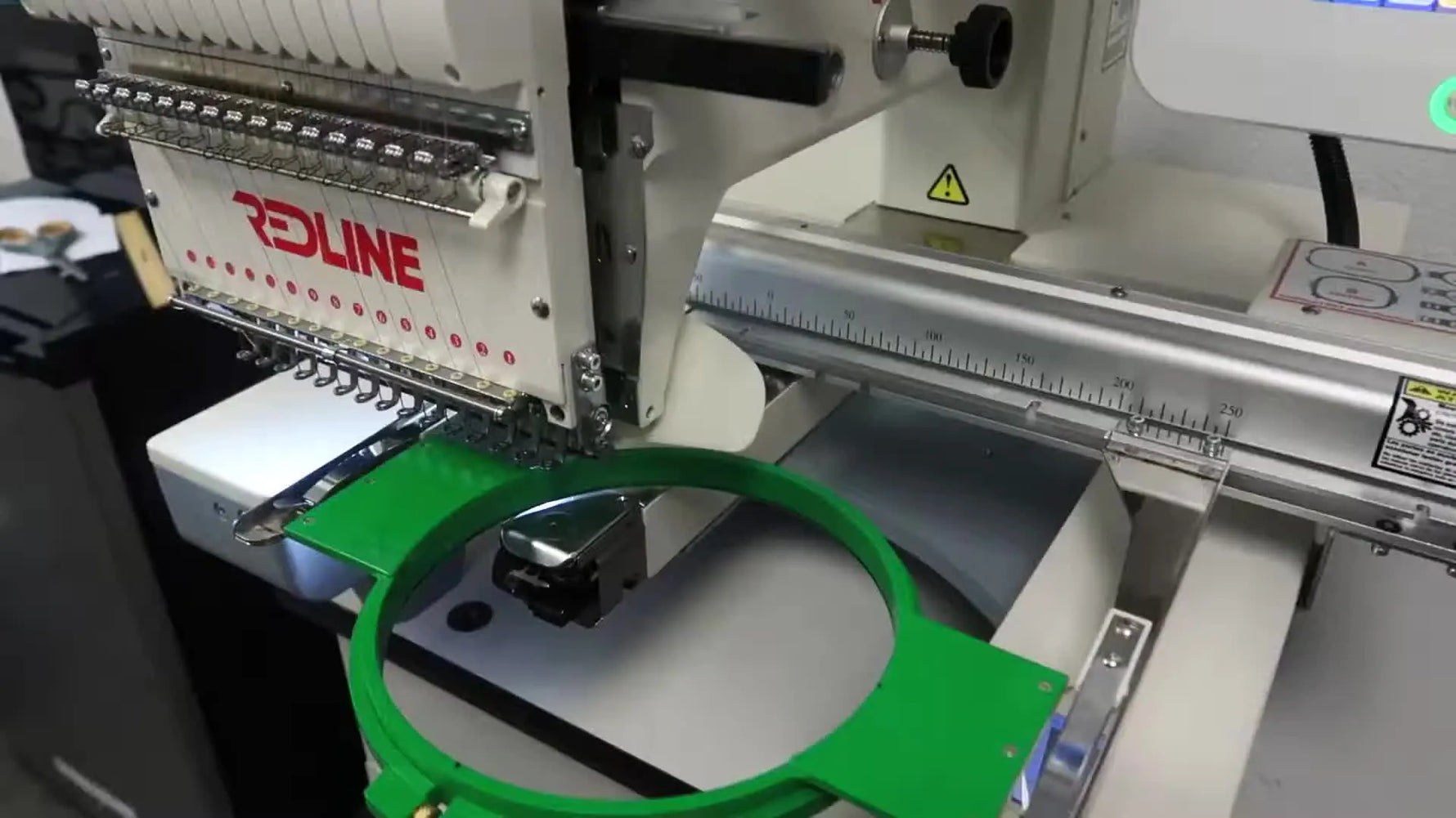 A side view of a Redline BECS-285 with a green round hoop installed, showing the pantograph area where frame limits protect the presser foot from the hoop rim.