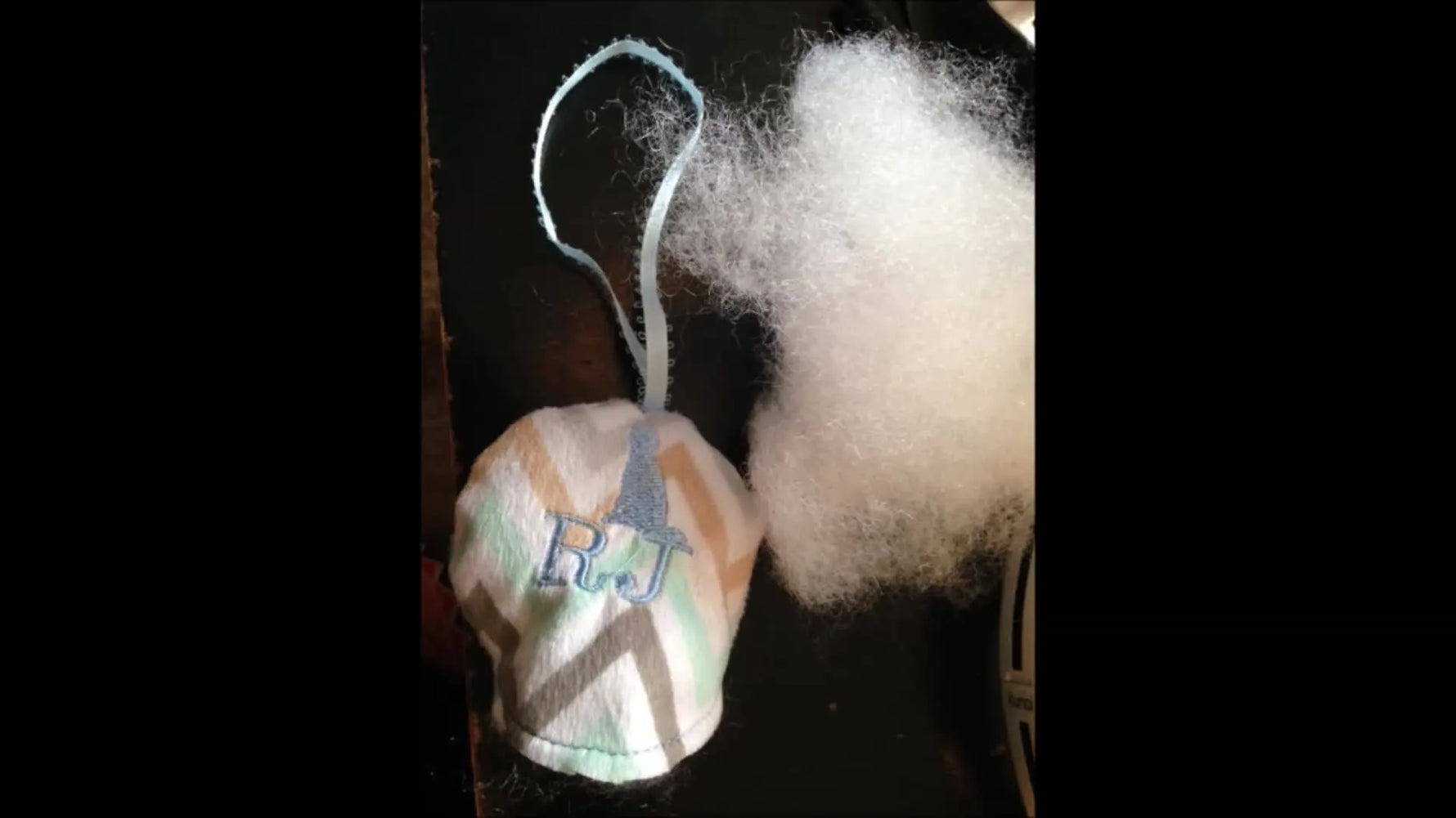 Two finished in-the-hoop circle stuffies with ribbon loops are shown overhead beside scissors, highlighting the final stitched seam and turning gap.