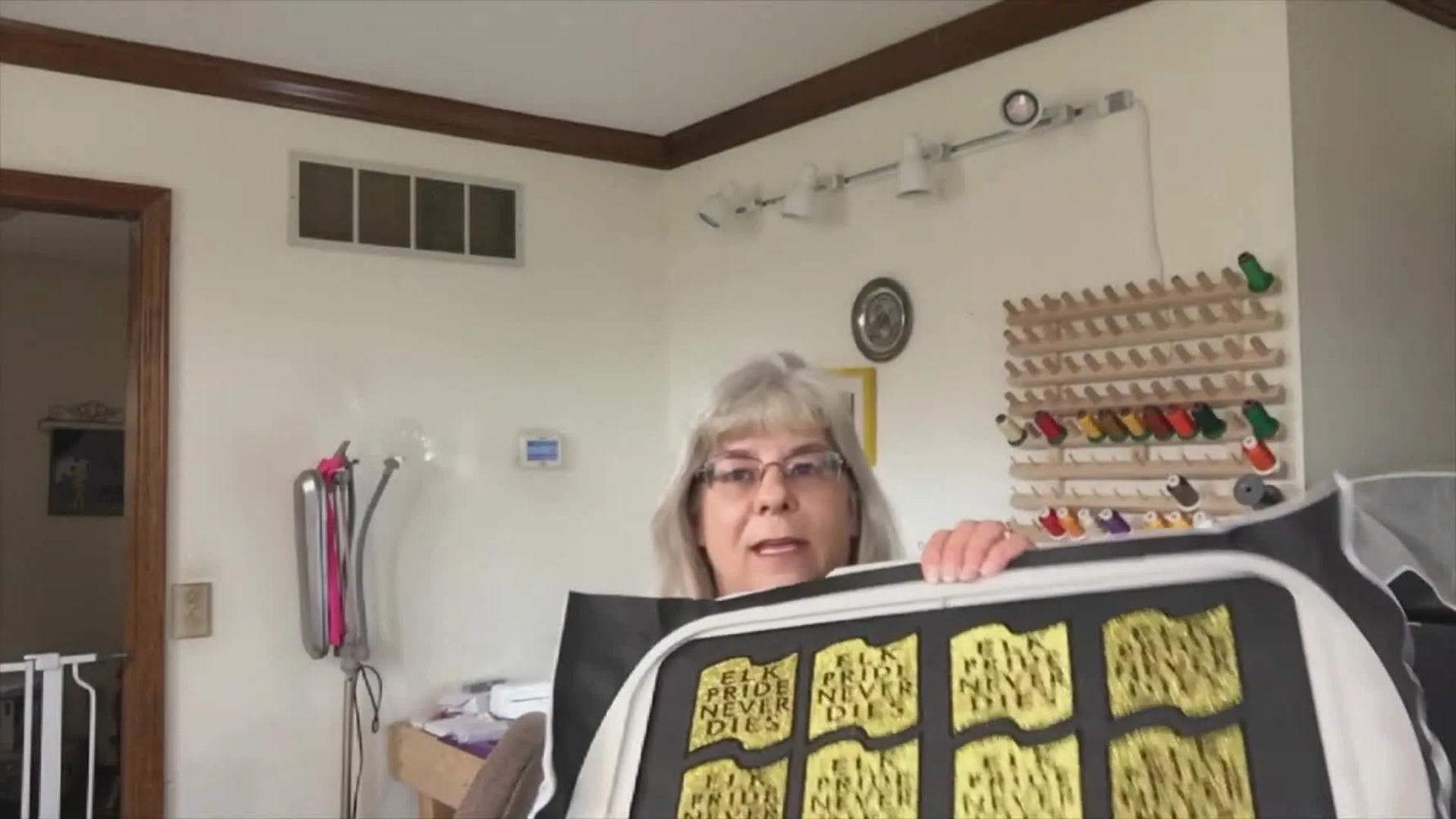 A large embroidery hoop holding a full batch of 12 finished school badges, showing what efficient multi-design production can look like when the stitch path is organized.