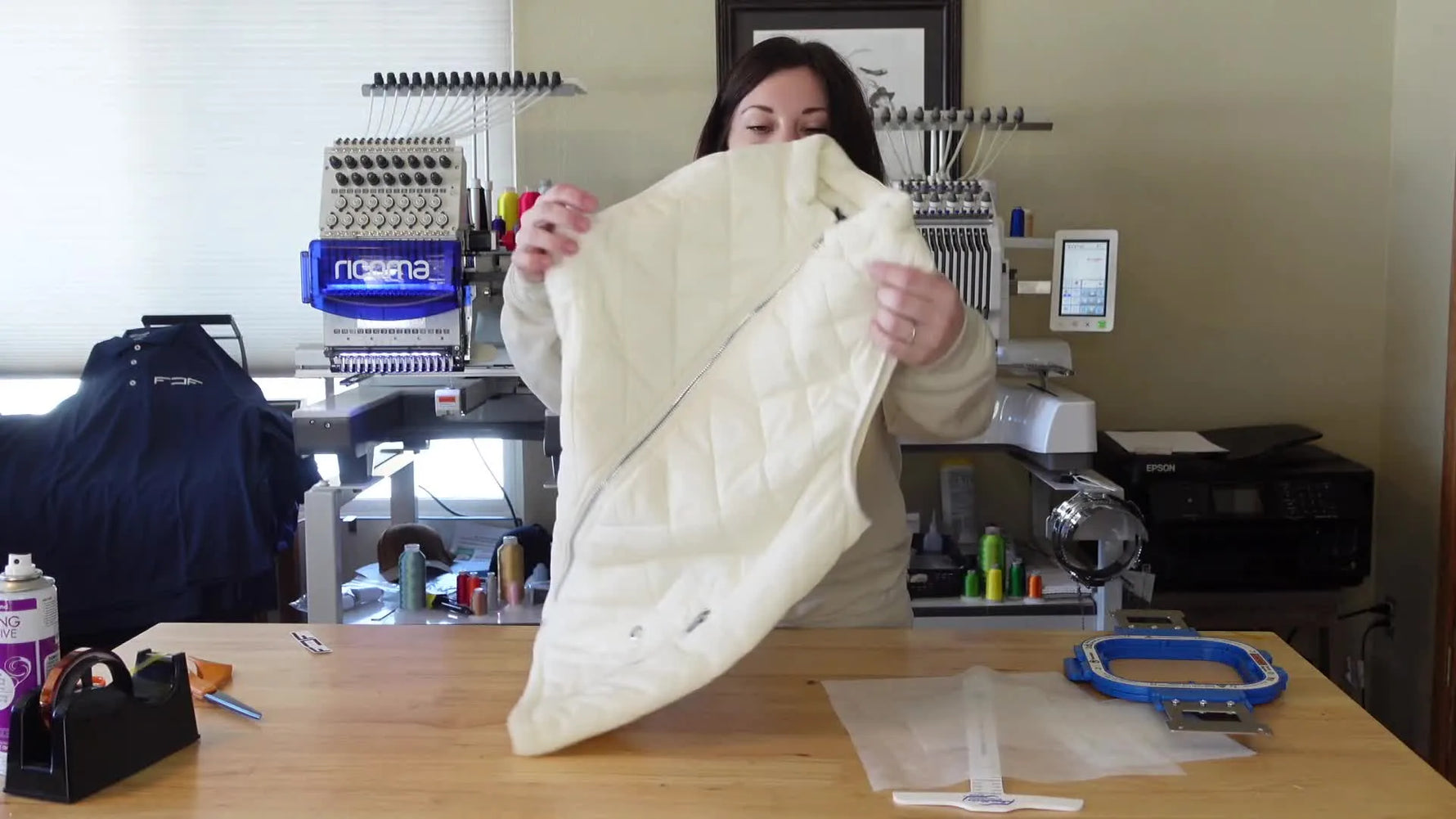 Woman holding up a cream-colored puffy vest, showing its quilted texture.