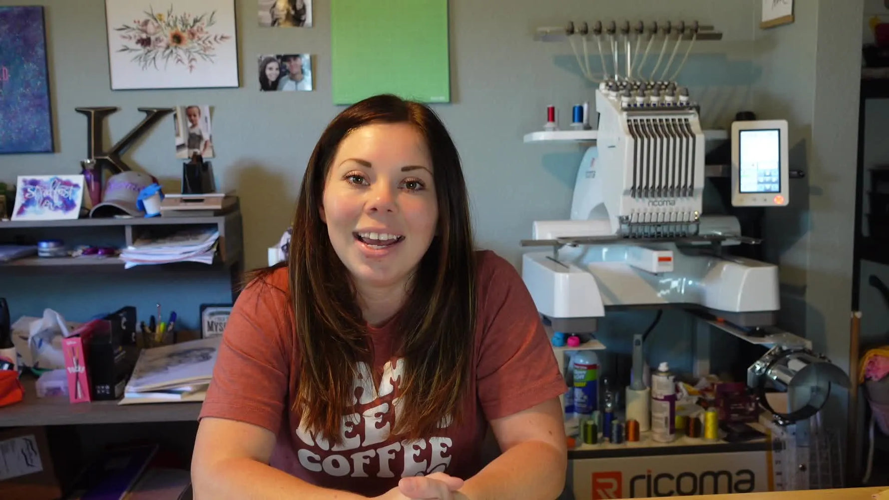 Woman introduces a machine embroidery speed test, sitting in front of a multi-needle machine with a single-needle machine visible in the background.