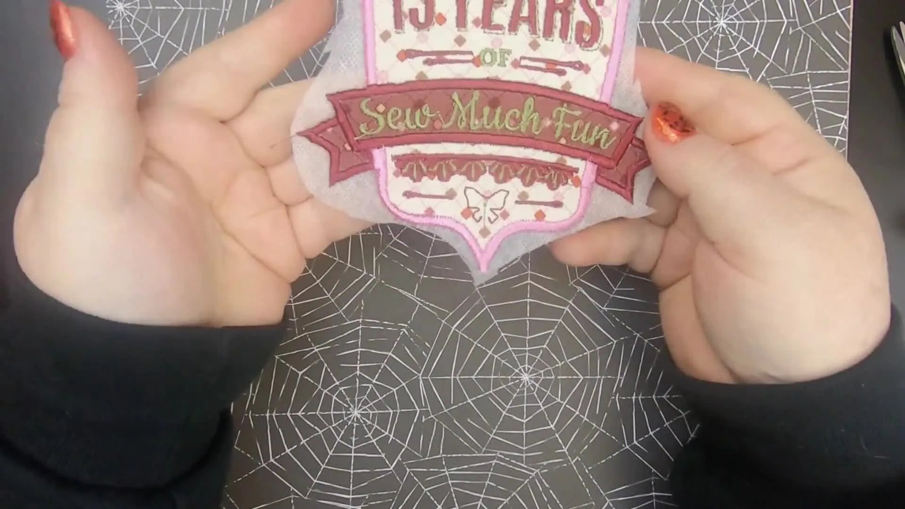 A finished “15 Years” commemorative embroidery patch is held up close so you can see the satin border, lettering, and accent stitching clearly.