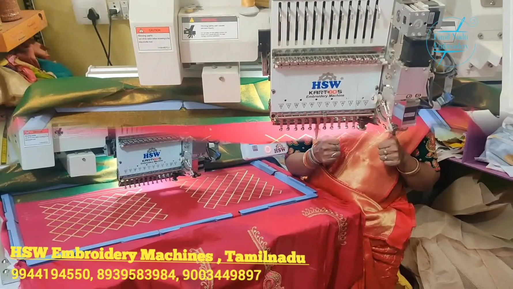 Overhead view of red silk clamped flat with blue magnetic bars while a gold diamond grid pattern is being stitched on a large border frame.