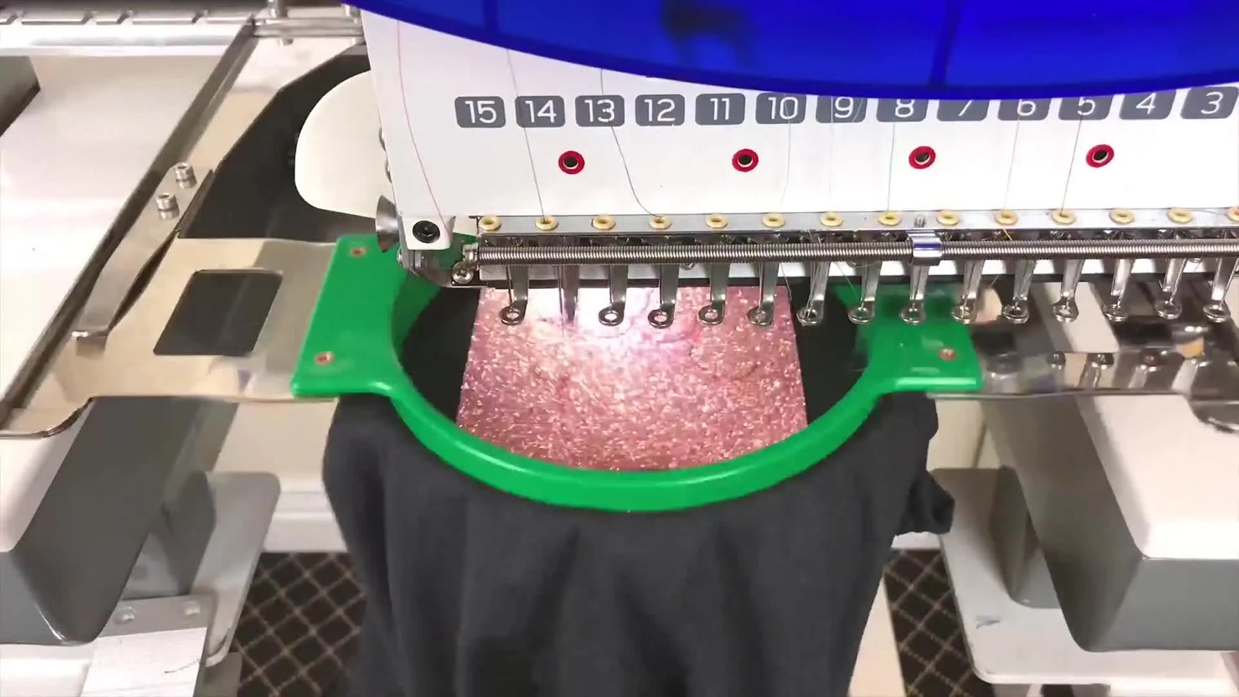 A close-up of a Ricoma embroidery machine stitching a satin border directly onto glitter HTV inside a tubular hoop.