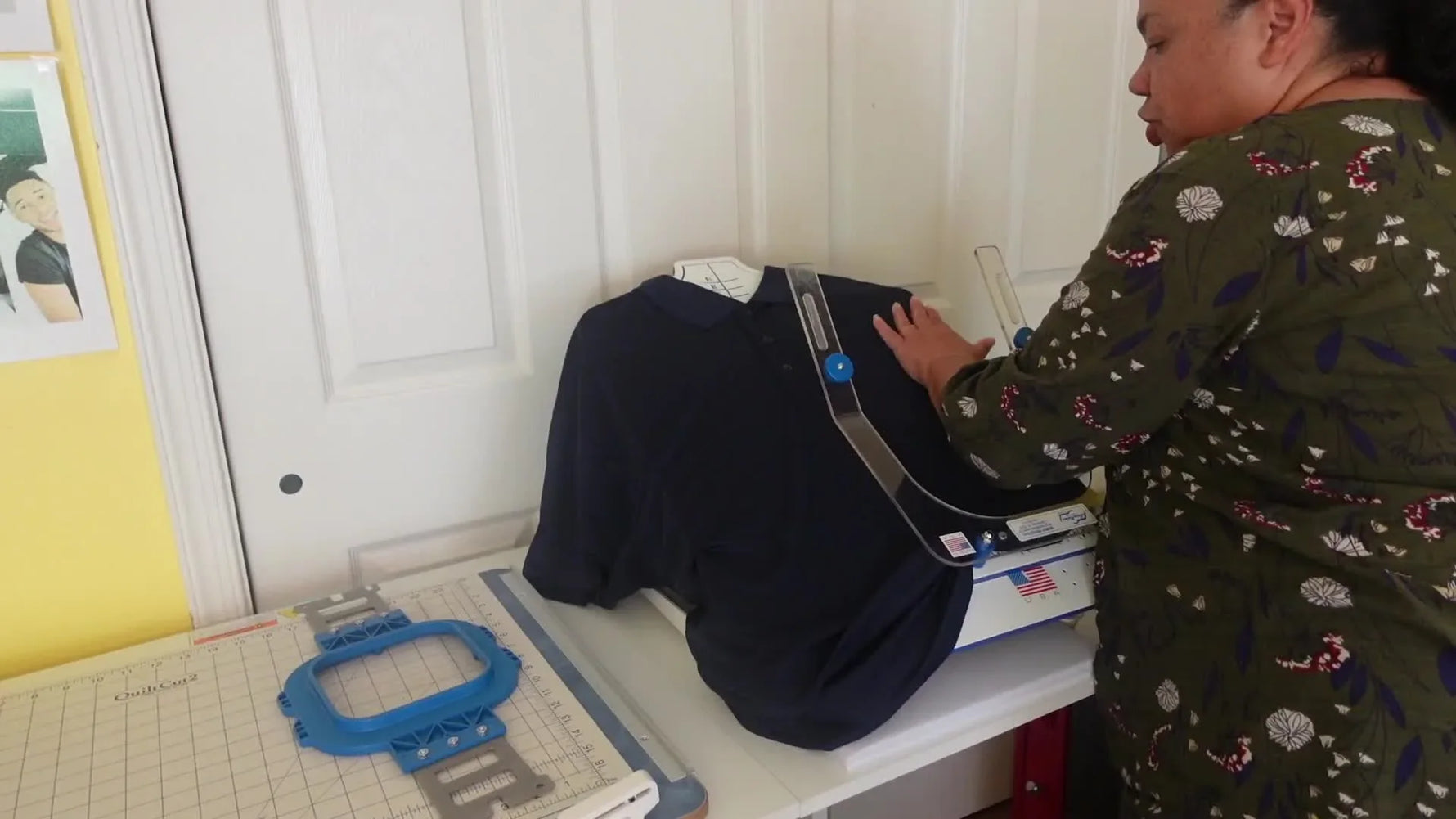 Hands gently smooth a navy dry‑fit polo onto a hooping station so the fabric bonds evenly to the stabilized backing before the magnetic hoop snaps on.