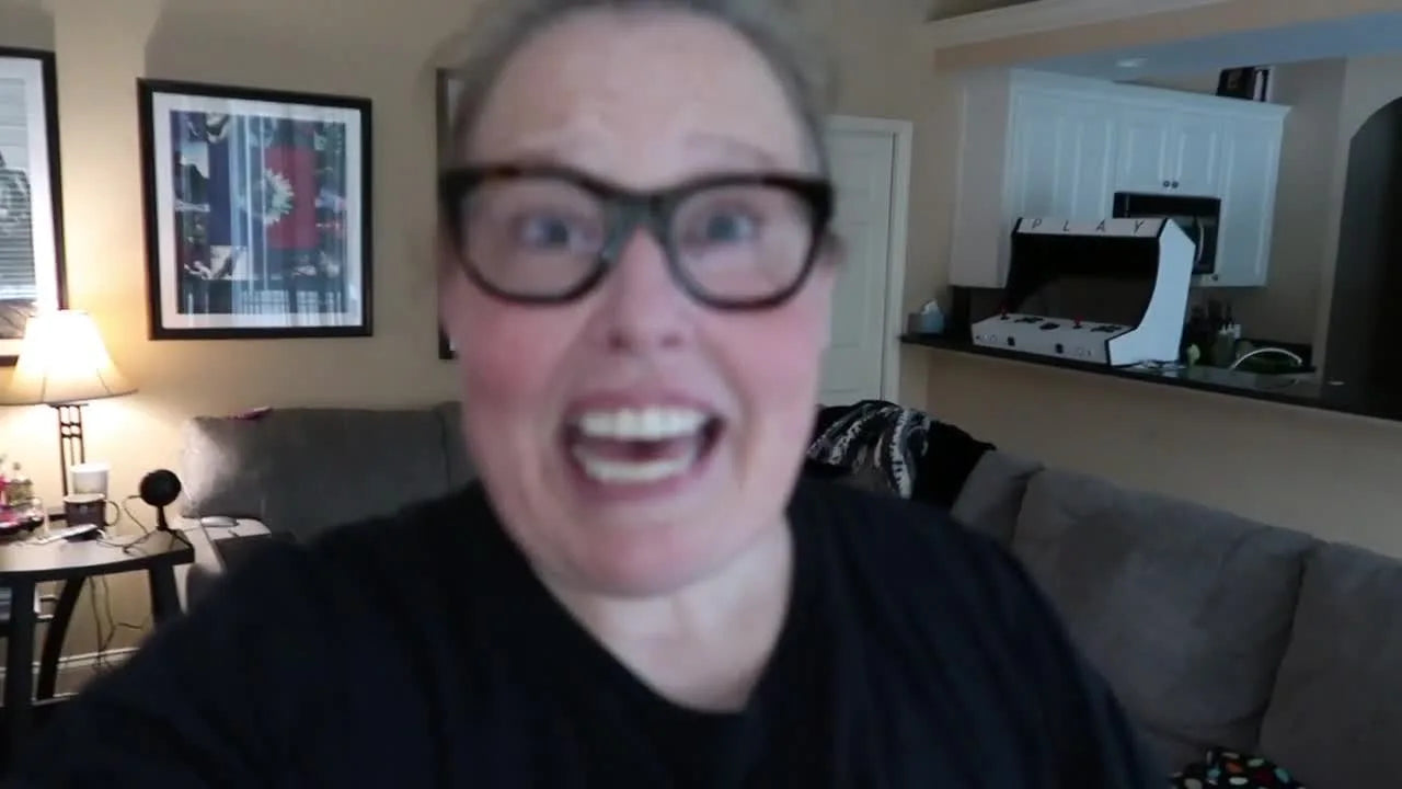 Woman in glasses speaking to camera, introducing tutorial on merging embroidery designs.