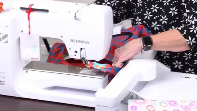 A hooped finished tote bag slides onto the embroidery module while the rest of the bag tunnels safely under the machine’s free arm.