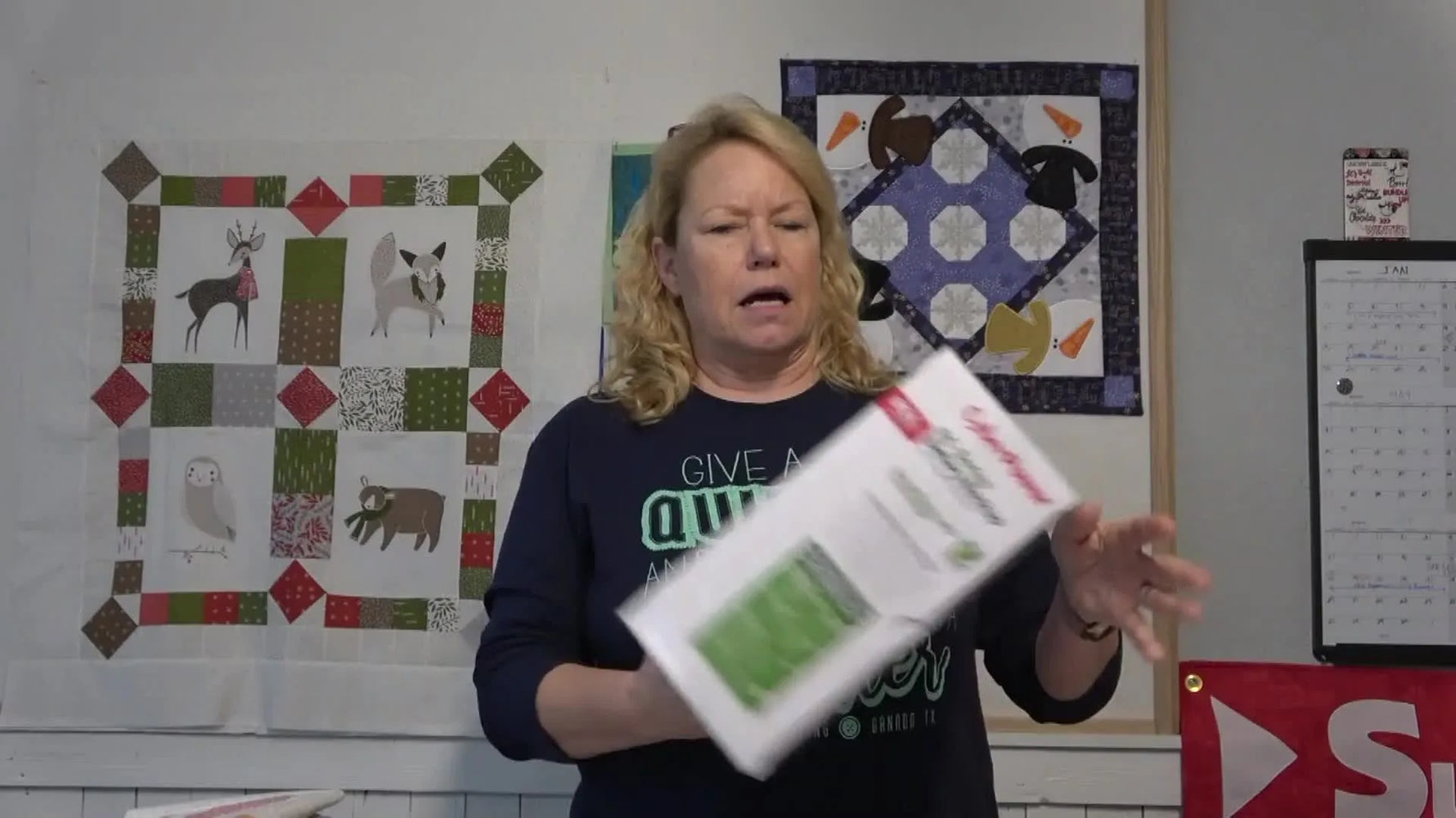 Becky holds a CyberPower battery-backup UPS box, the kind of protection that can save an expensive embroidery machine during surges and outages.
