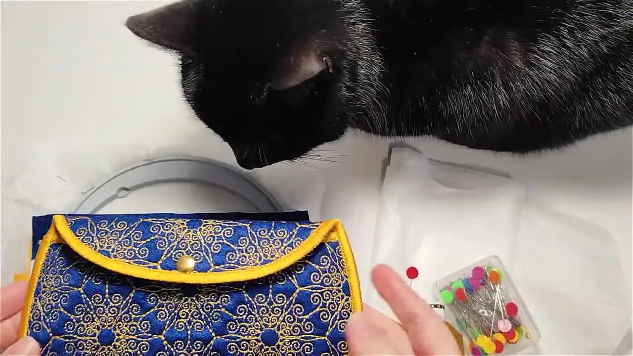 A close-up of the finished blue-and-gold quilted ITH glasses case, showing the ornamental quilting and clean satin-stitched edge.