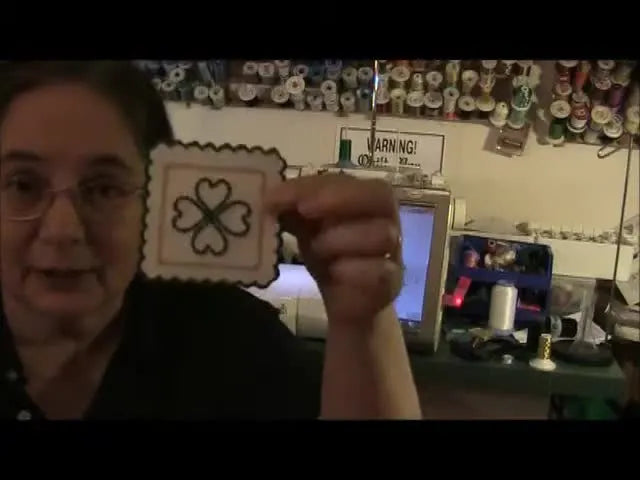 A finished 4-leaf clover coaster with a gold inner frame and a clean green scalloped edge is held up for a close look.