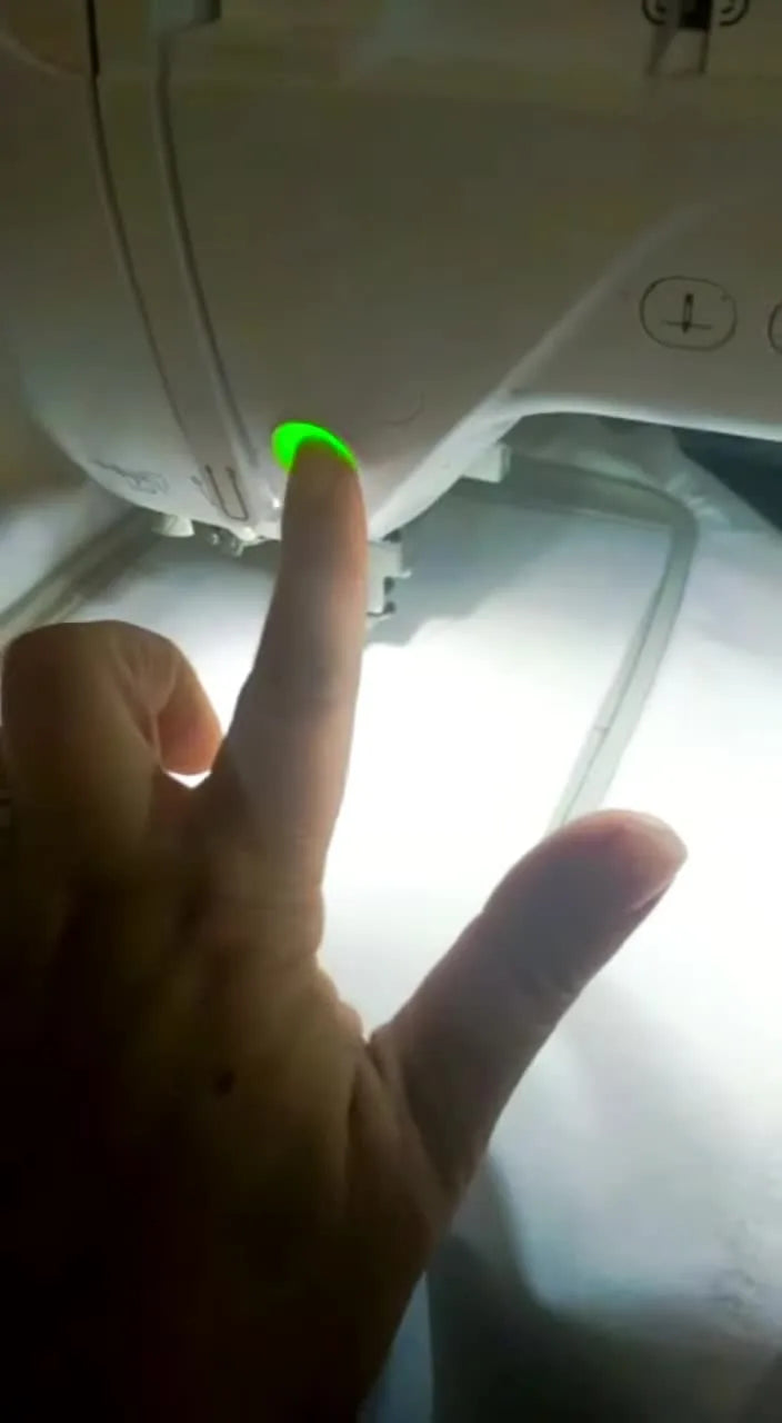 A close-up action shot of the Brother Innov-is F440E stitching a gold crown outline at speed on hooped white cotton.