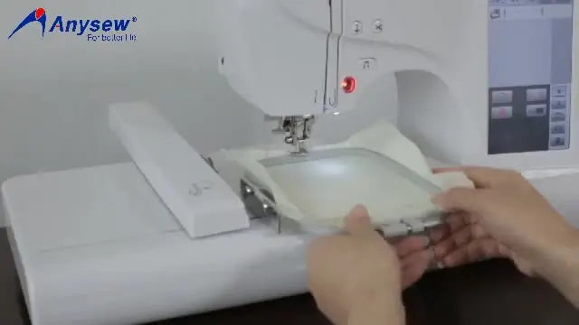 A close-up of the loaded embroidery hoop snapping into the machine carriage, right before stitching begins.