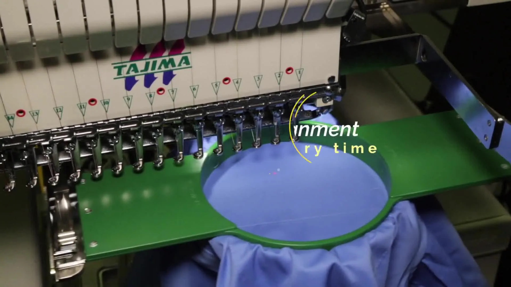 A red laser traces the design boundary on a slanted shirt pocket held in a green magnetic hoop, showing the design rotated to match the pocket angle.
