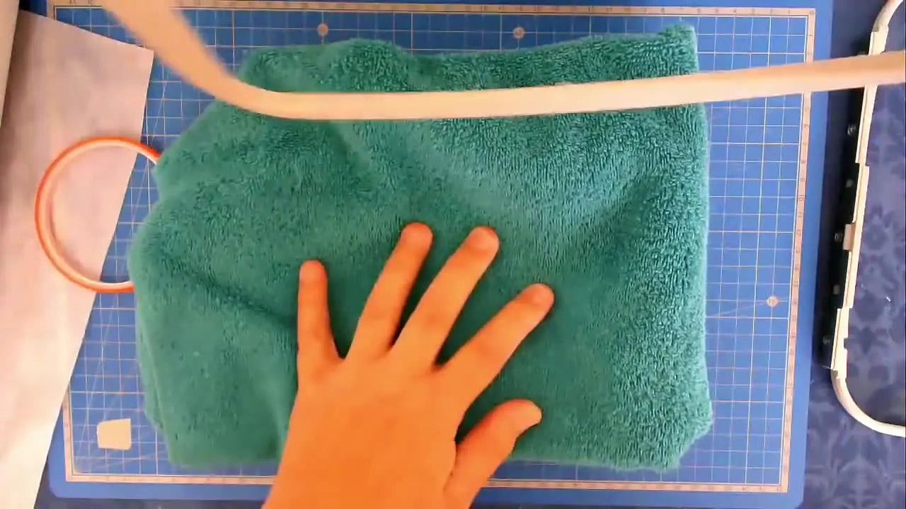 A close-up of the inner hoop ring being pressed onto a towel to de-tack double-sided tape into a clean, high-friction grip.